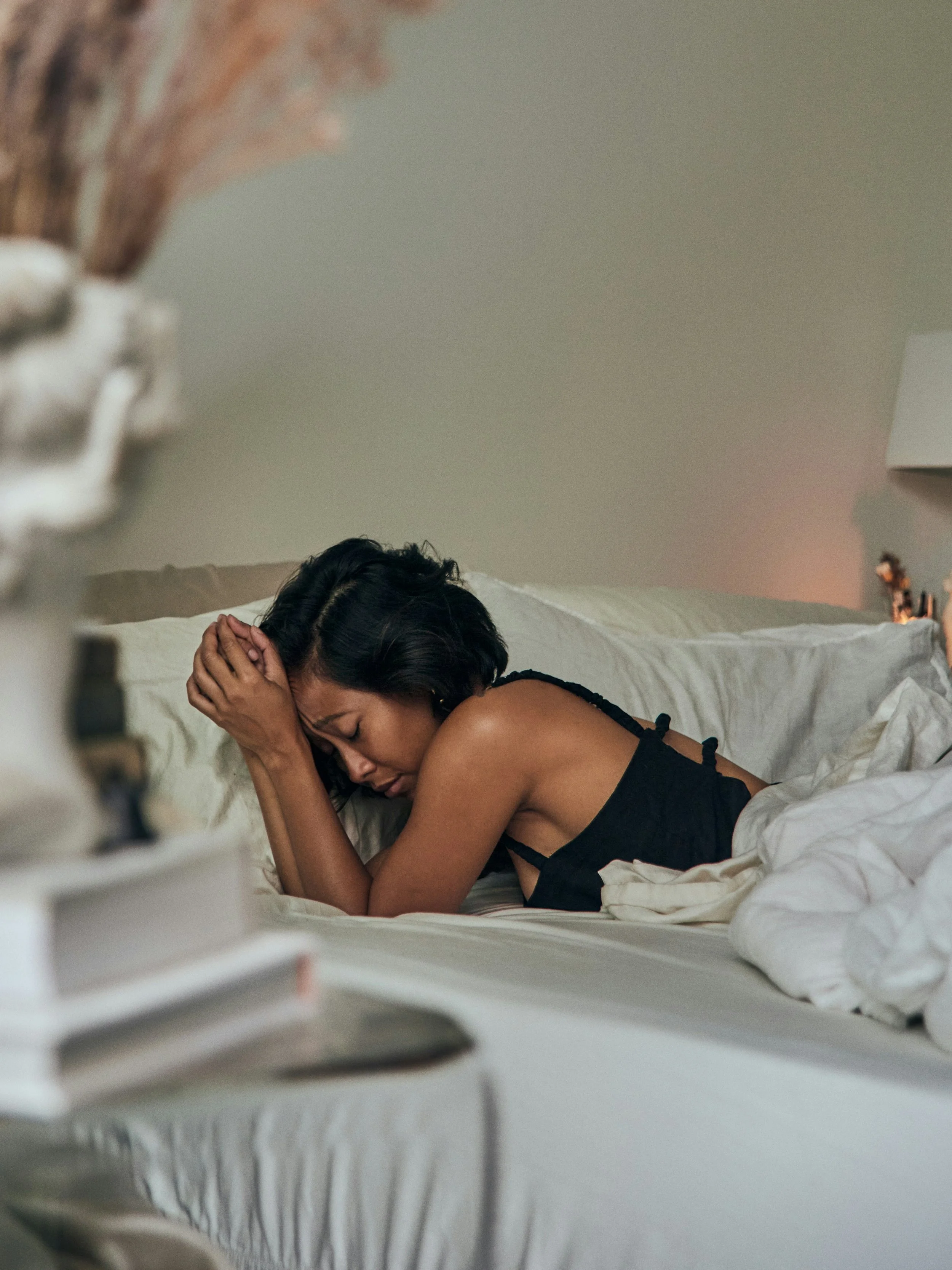 Woman lying in bed feeling overwhelmed and ashamed after an emotional reaction, reflecting nervous system shutdown and withdrawal in relationships