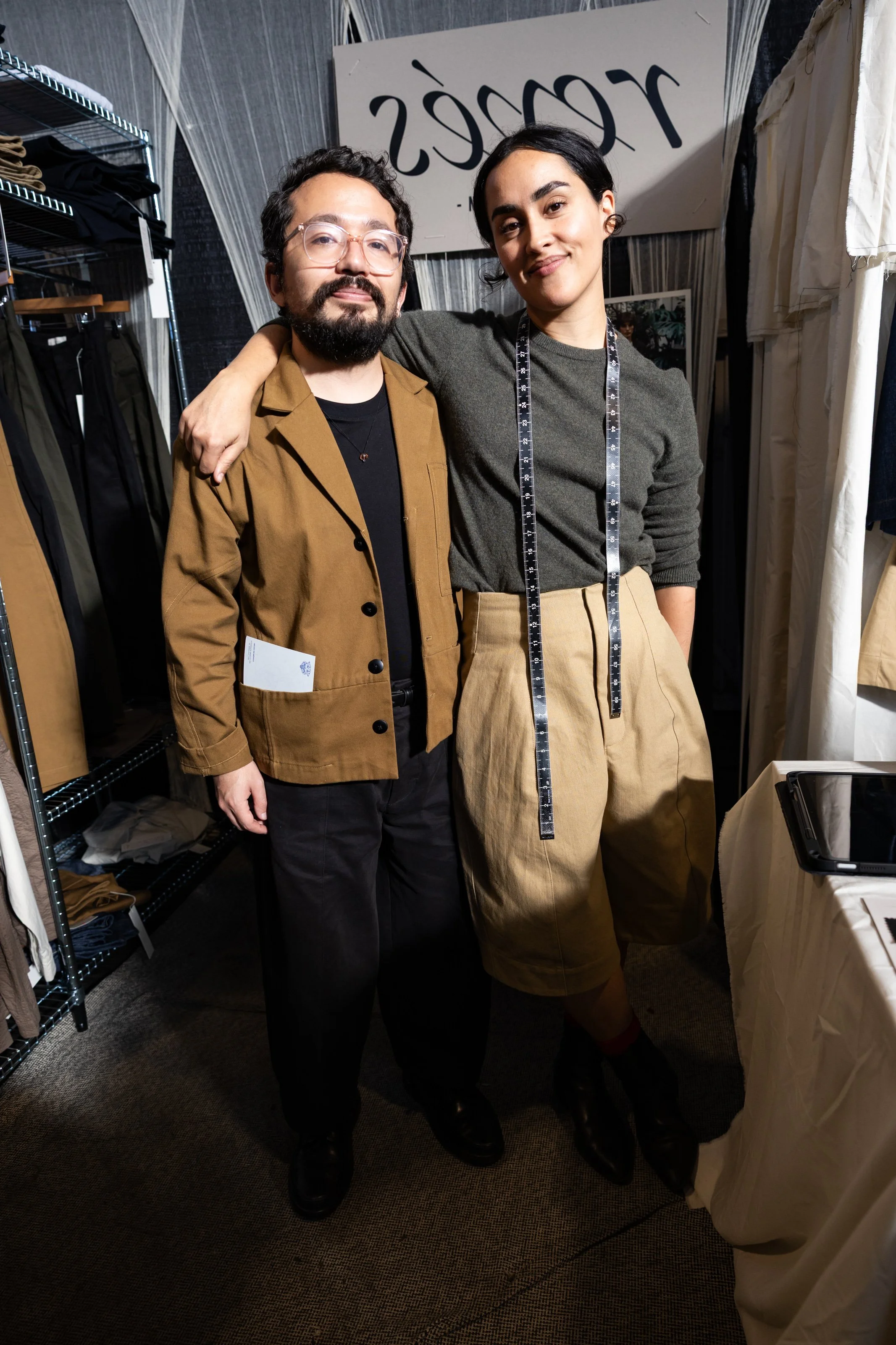 Couple wearing earth-toned clothing posing together.