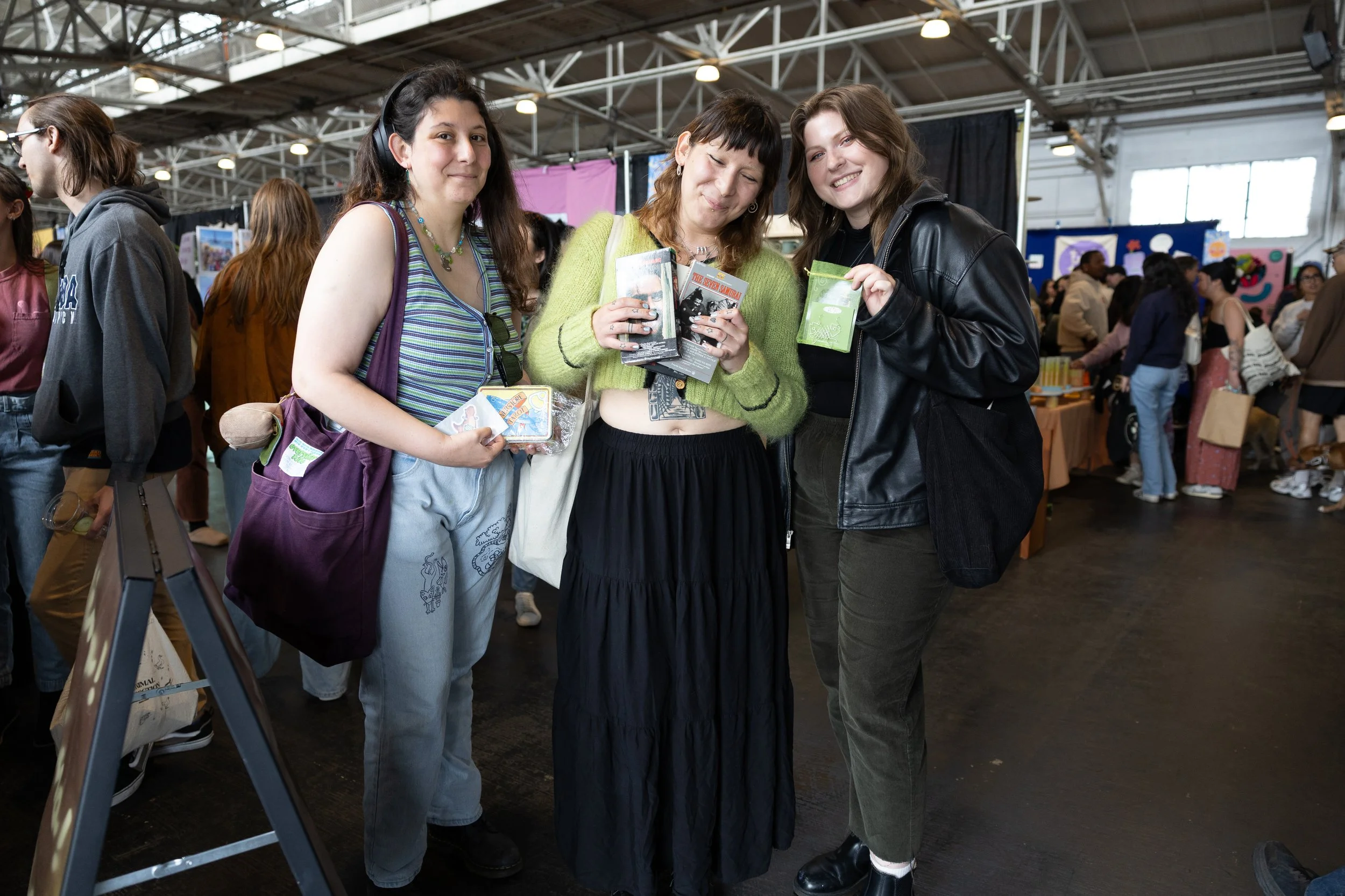 Three friends smiling and posing at an indoor market.