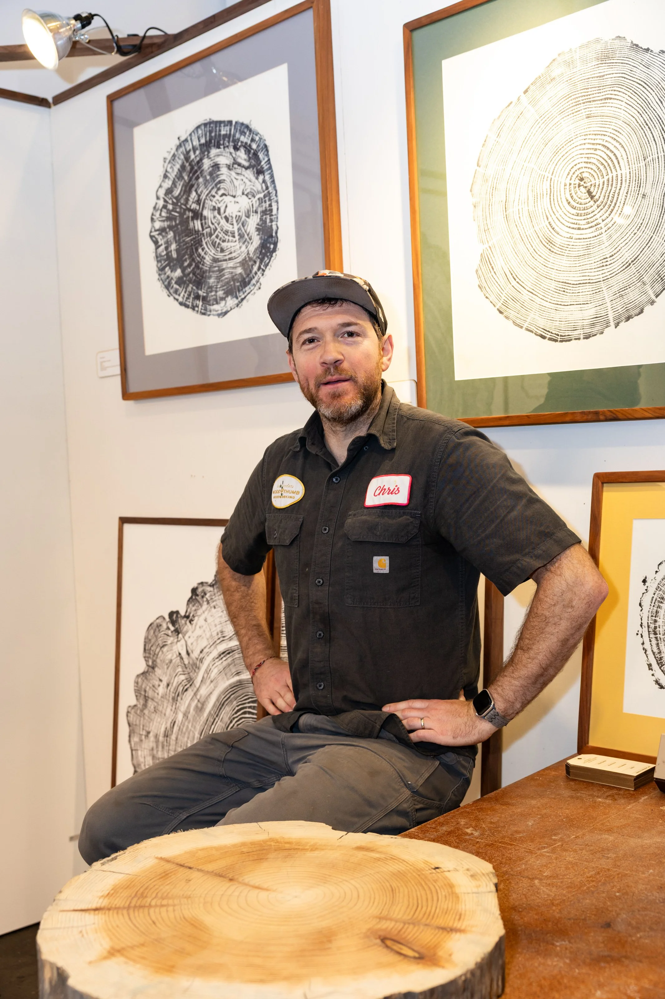 Smiling man posed in front of a wall of framed woodblock prints.