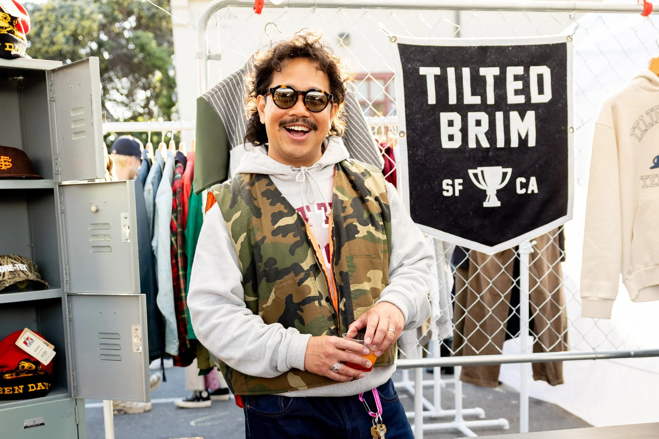 Smiling man posing in front of a display of clothing and accessories.