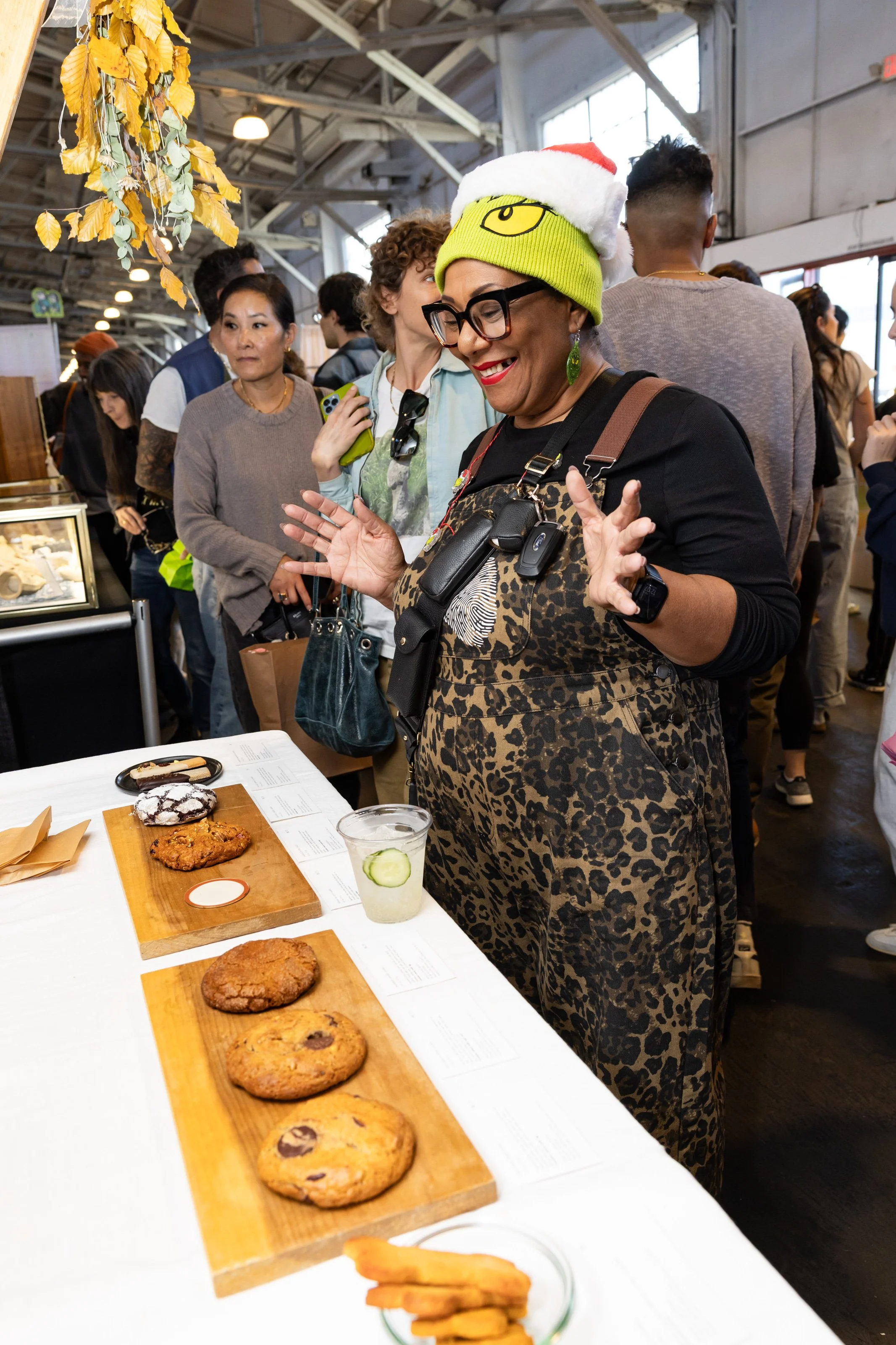 Smiling woman standing in front of a table of cookies displayed.
