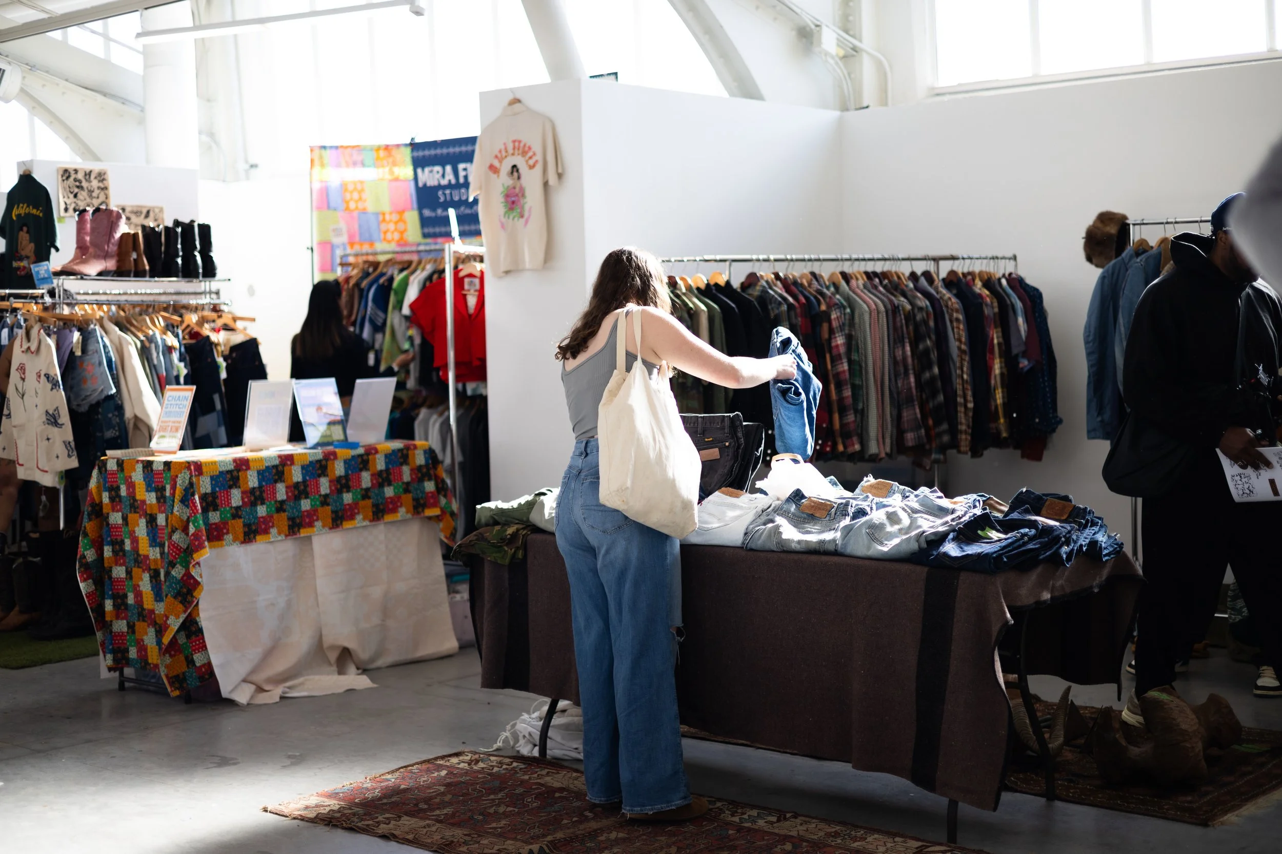 Woman looking through clothing displayed on a table at an indoor market.