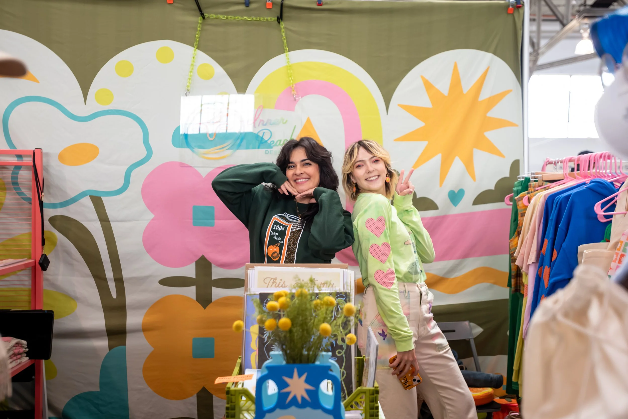 Two women posing in a clothing display booth.