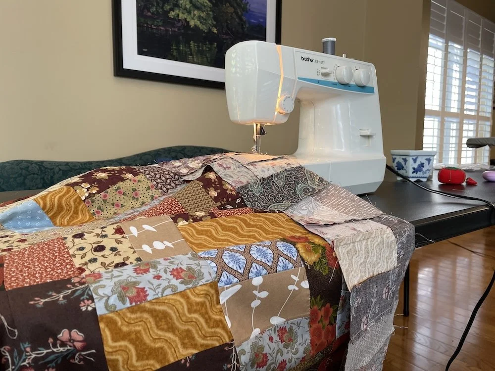 A sewing machine with pieces of a quilt under the sewing needle