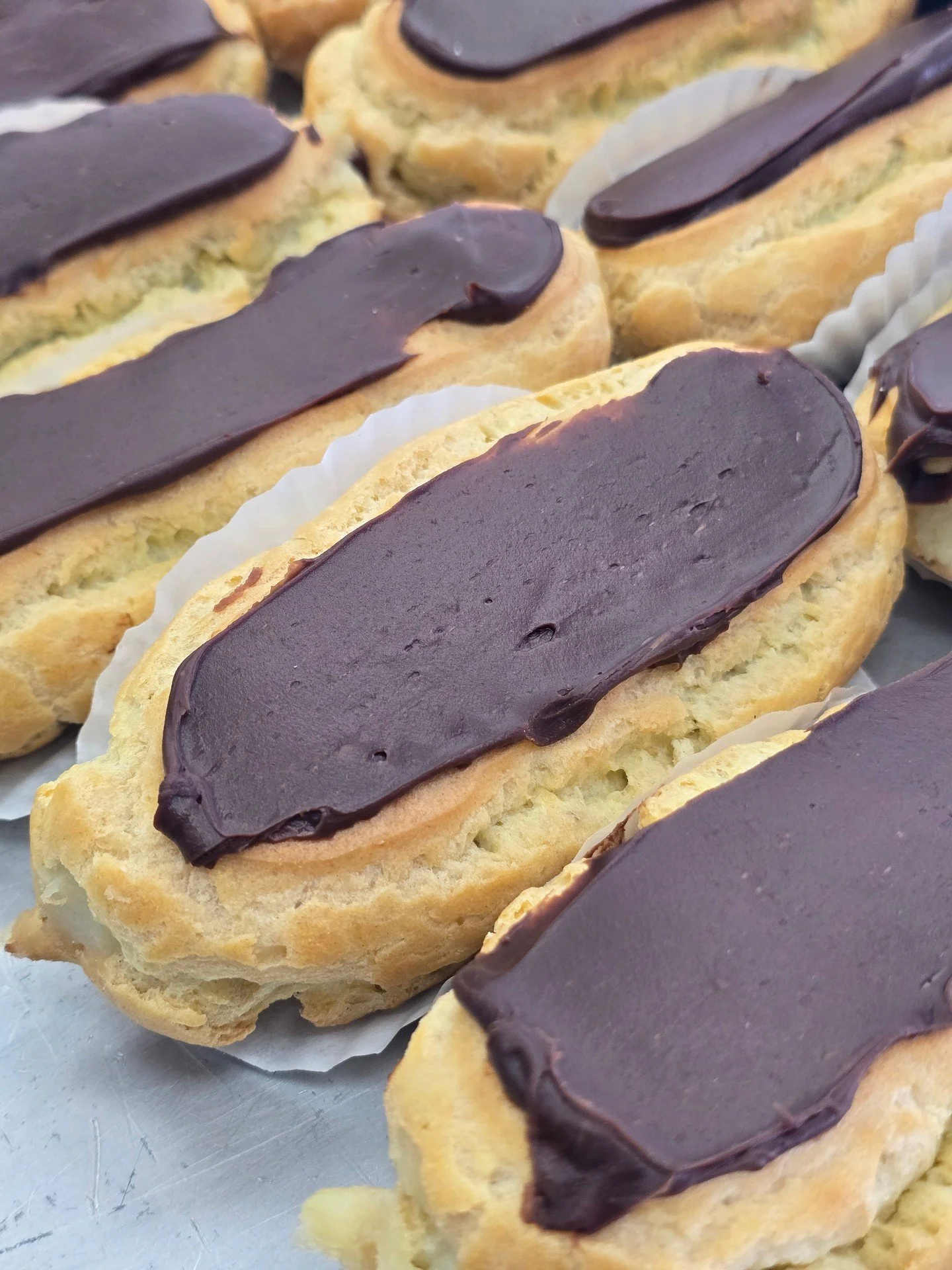 Eclairs! Baked fresh everyday and filled with our vanilla custard topped with chocolate! #antoinespastryshop #pastry #pastries #french #chocolate #vanillacustard #richthebaker #custard