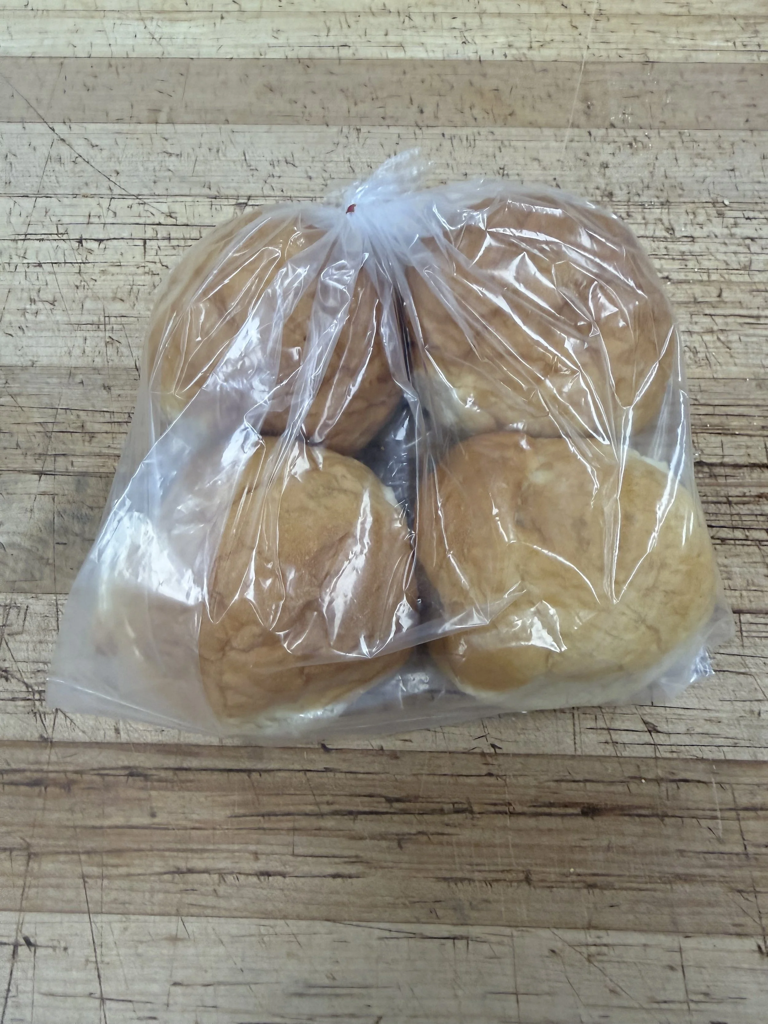 Four salted bread rolls on a wooden surface.