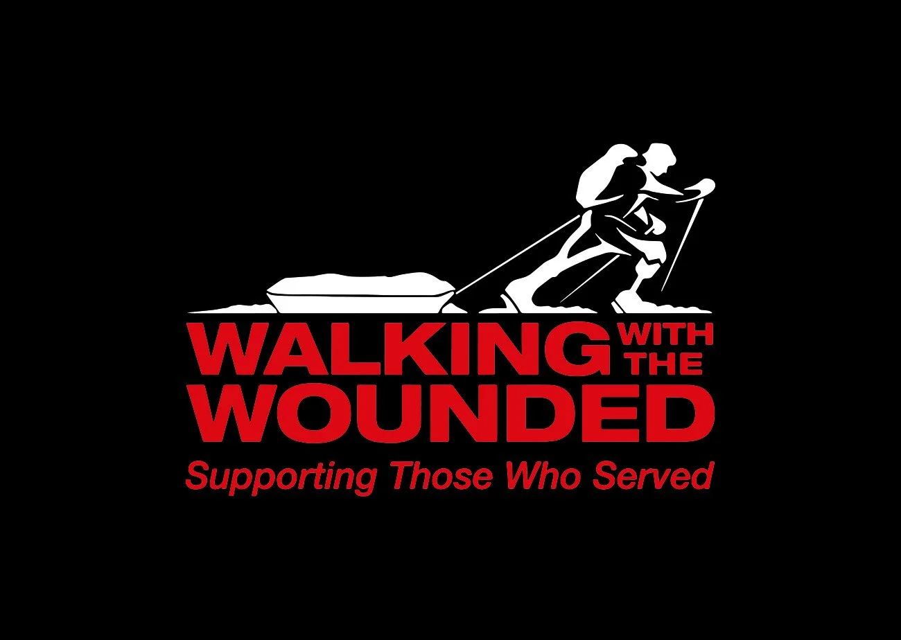 A logo with a soldier pulling a sled, with the text 'Walking with the Wounded Supporting Those Who Served' in red and black.