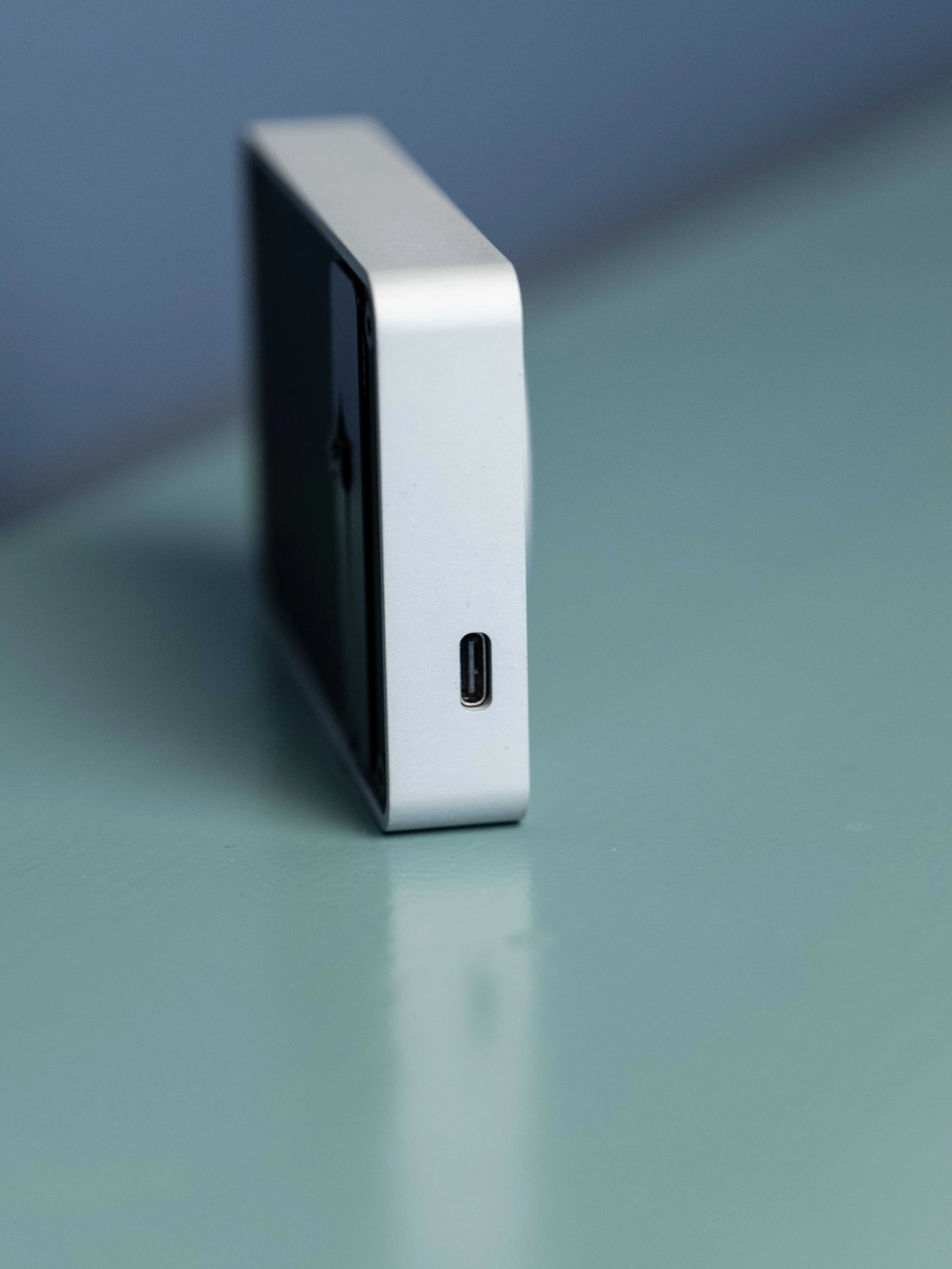Side view of the Pomodoro timer by Engineering Lab showing the USBC port and slim design against a blue and green backdrop