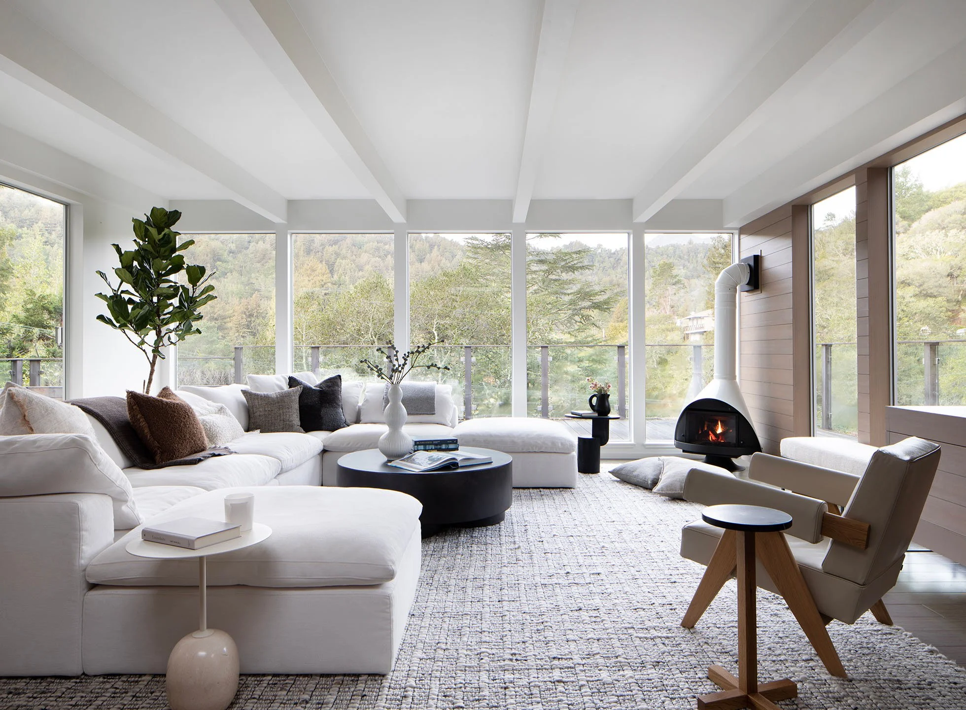 Interior styling by Nicole Johnson Design in Mill Valley featuring a light filled living room, panoramic windows, and modern sculptural fireplace