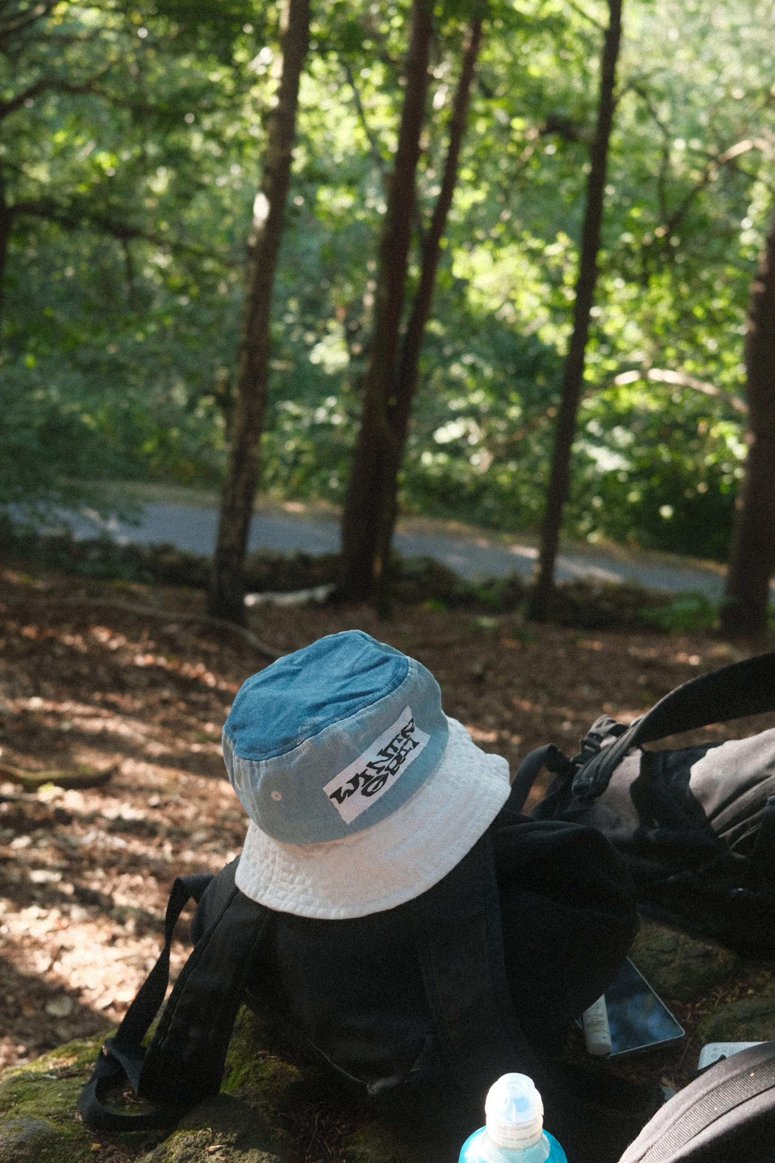 Climbing hat resting on a backpack in woodland near an outdoor bouldering area.