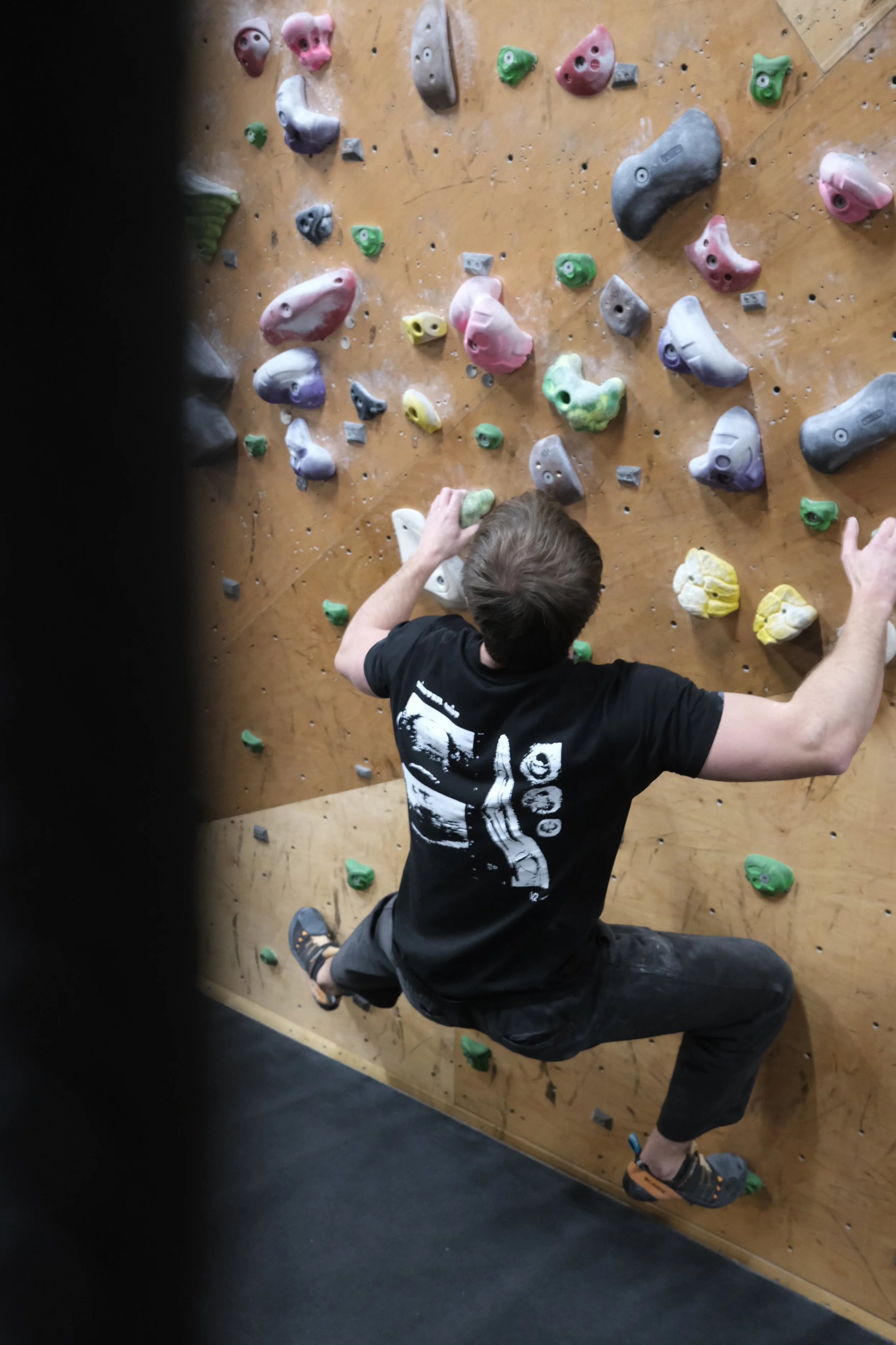 Rear view of a boulderer wearing the Winter Grit Rest Day Volume 2 T-shirt, showing the large white graphic back print.