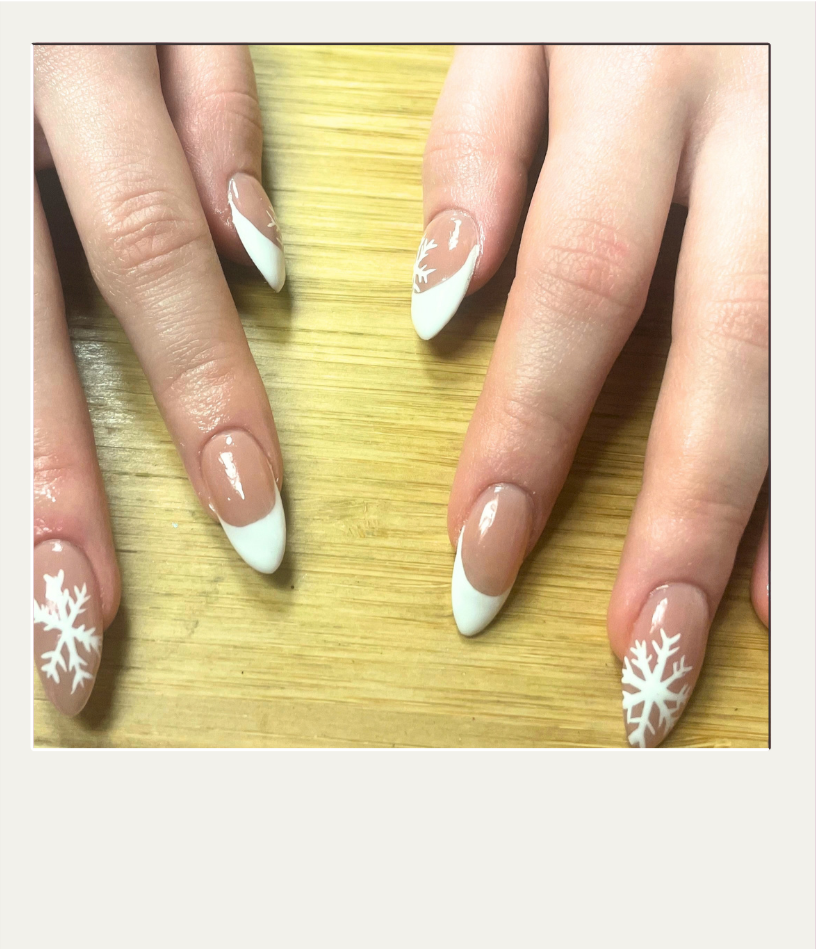 Nail art featuring classic French tips with white snowflake designs on the ring fingers, on natural-looking nails with a glossy finish.