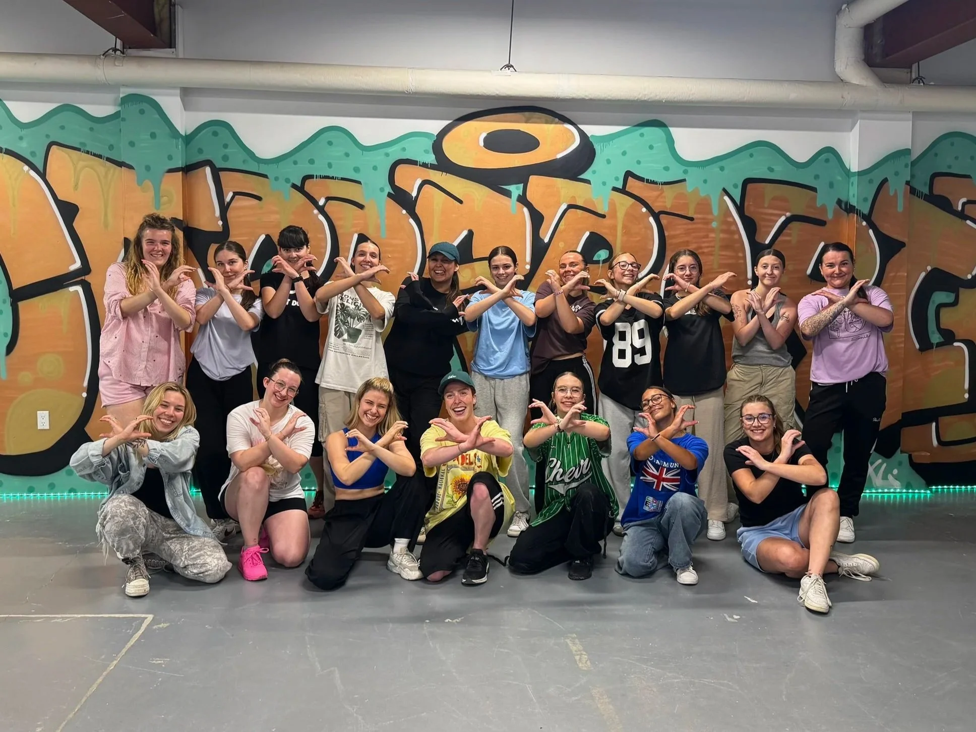 Groupe de jeunes femmes posant ensemble devant une fresque graffiti colorée du collectif de danse coppercrib