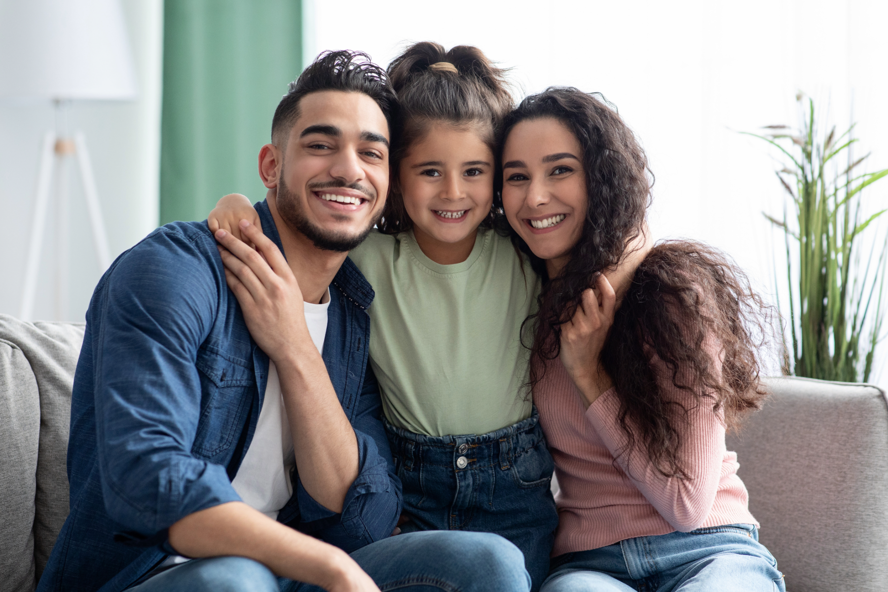 a child smiling in between her parents