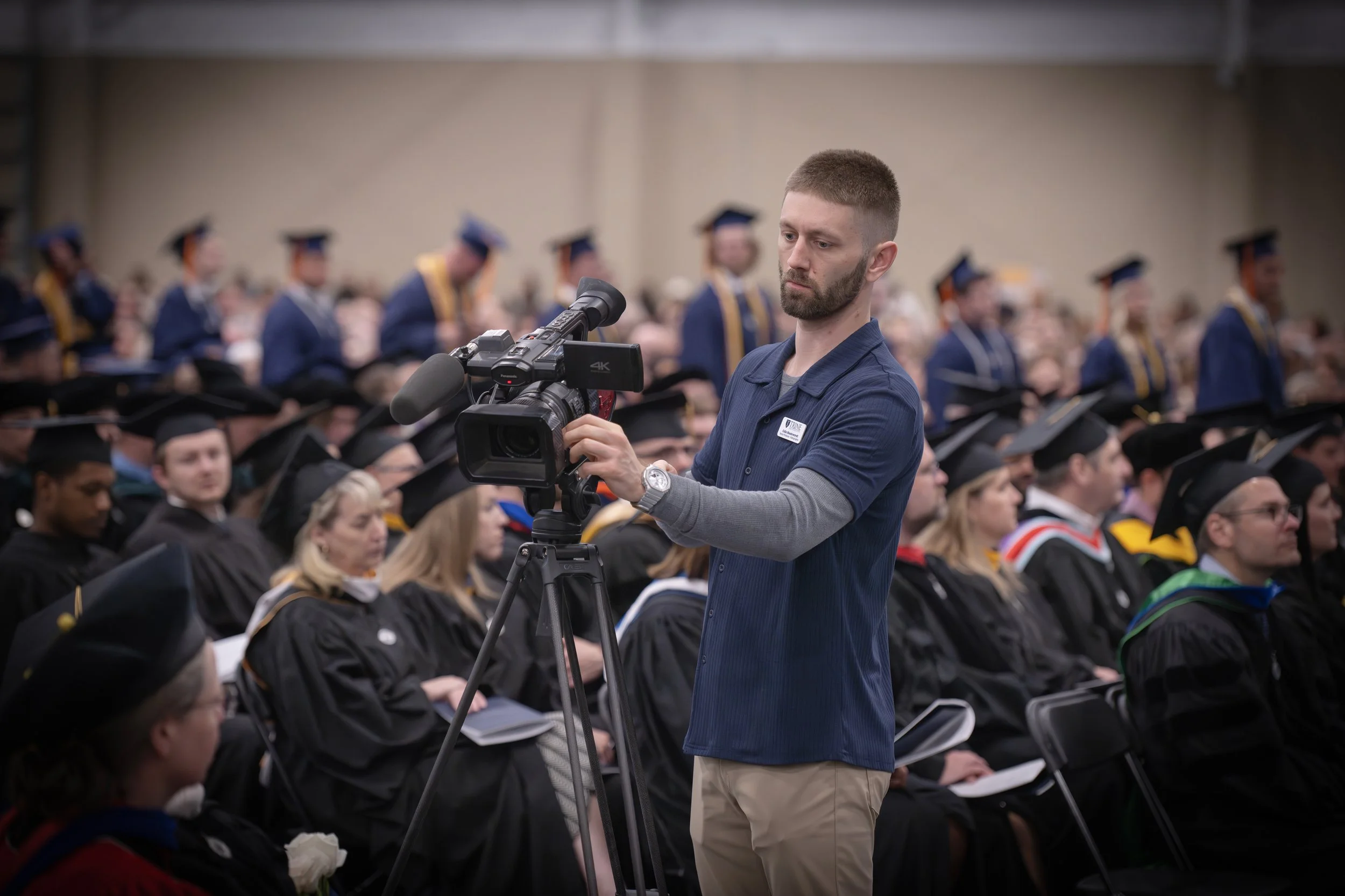 Two men are filming with a professional camera, one is looking at the camera while the other is partially visible.