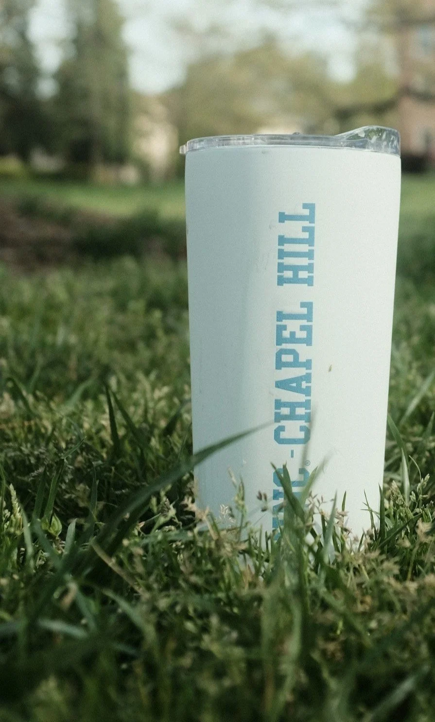 A UNC Chapel Hill tumbler sitting in green grass