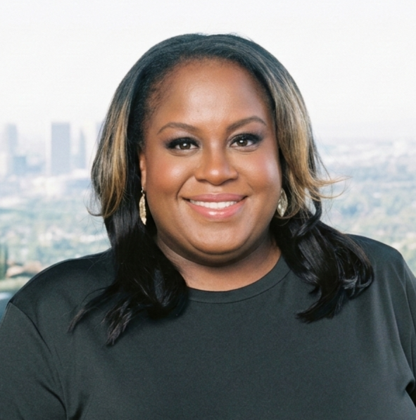 Close-up of a smiling woman with glasses, hoop earrings, layered necklaces, and a striped top, in an indoor setting.