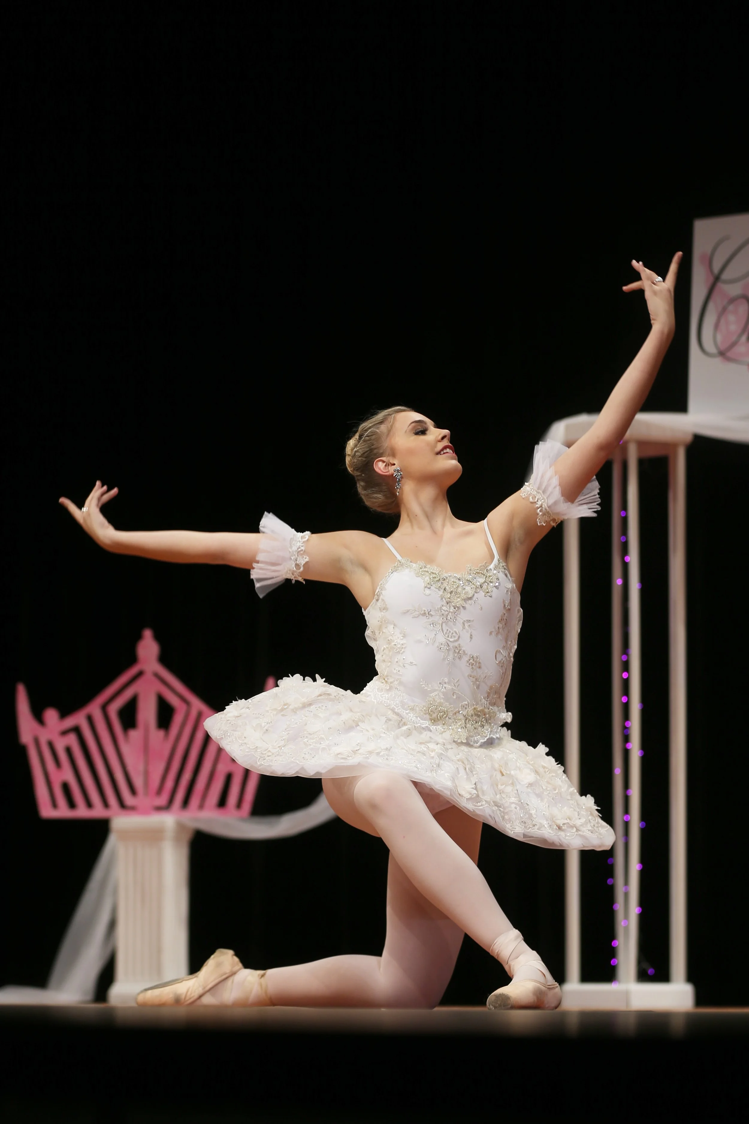 Ballet dancer in a white tutu performing on stage during a ballet performance.