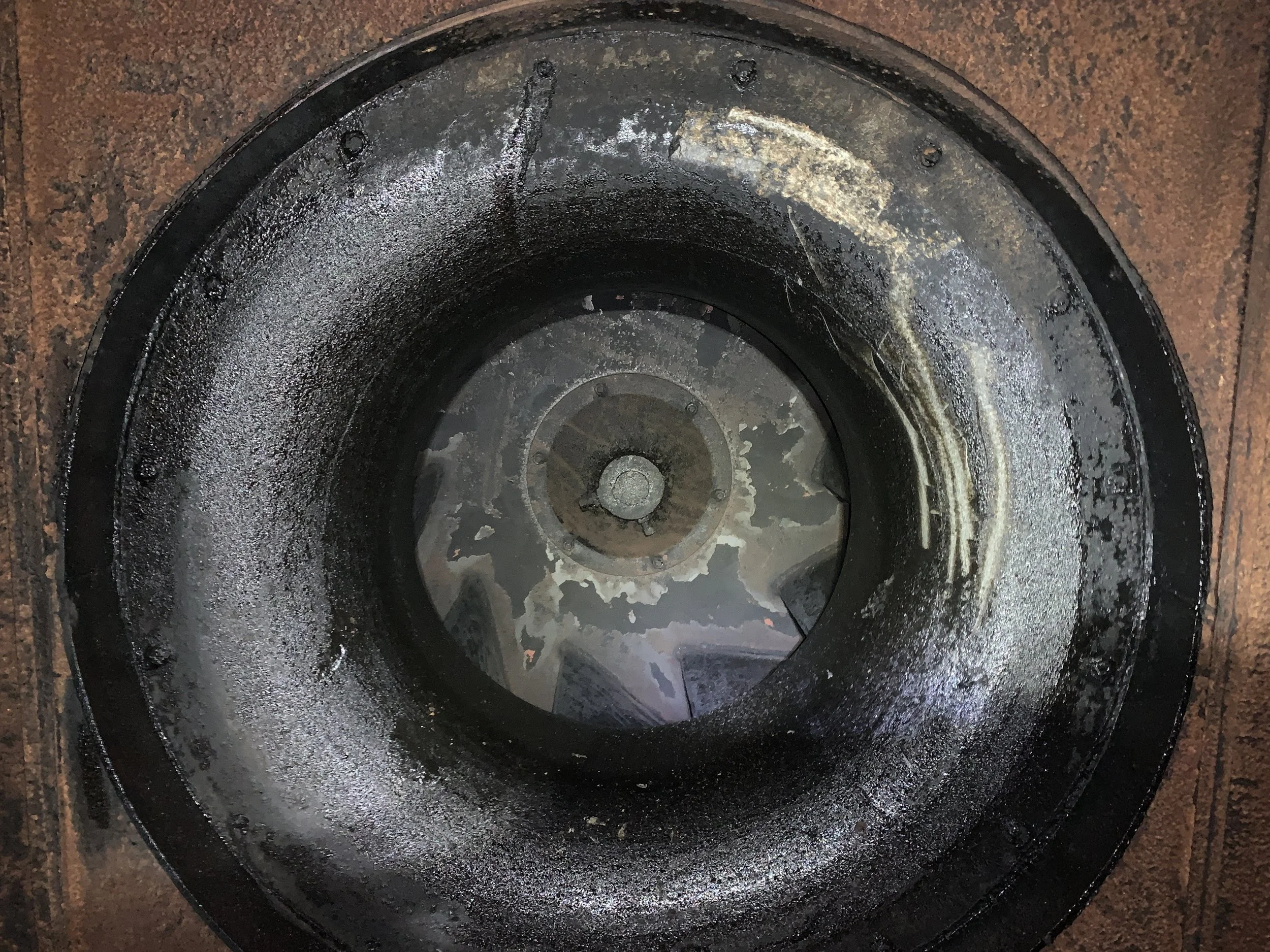 Close-up of a dirty kitchen exhaust fan with visible dust and grime buildup on metal surfaces.