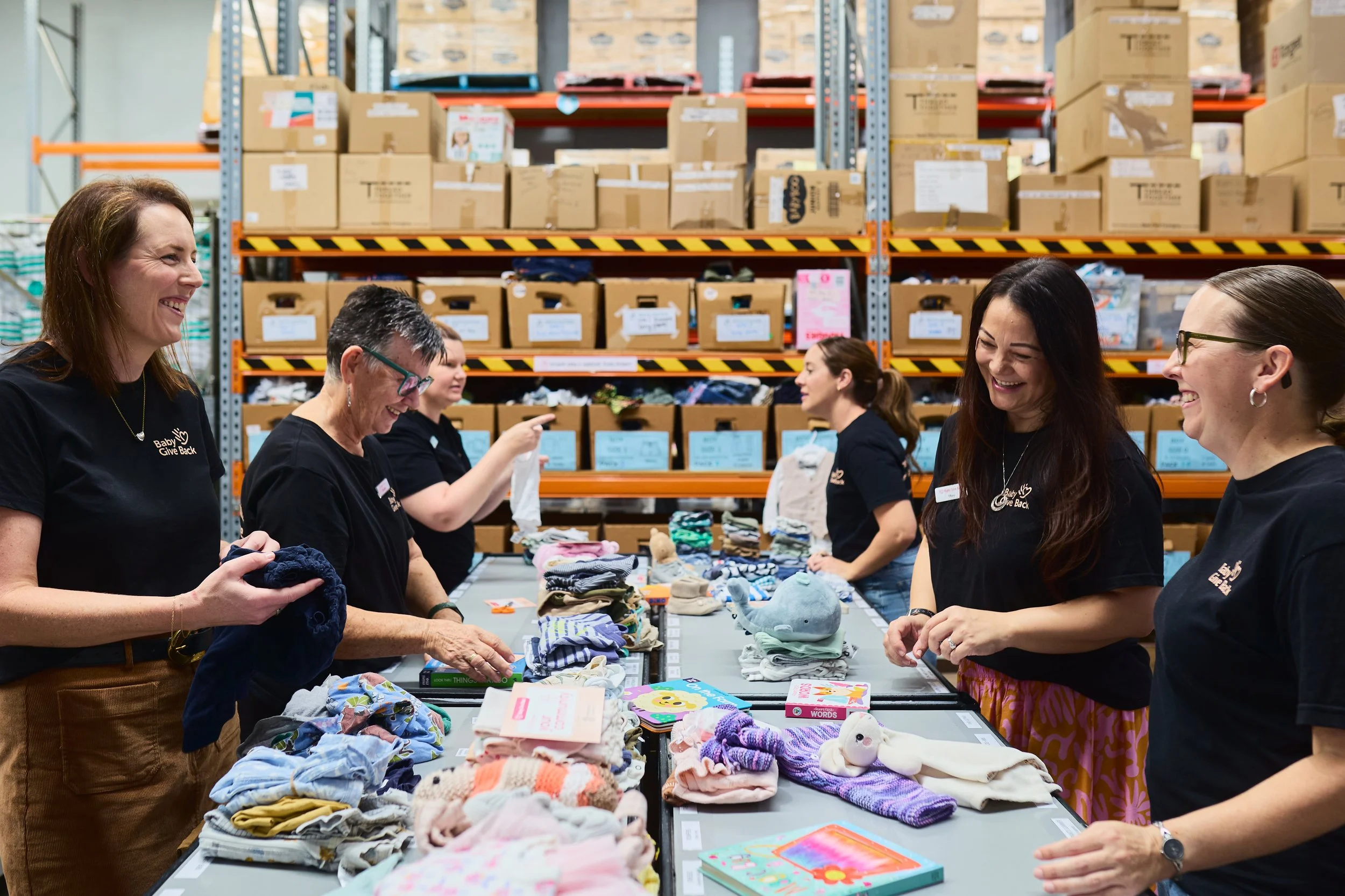 team and volunteers standing at table busy sorting and folding children's clothing