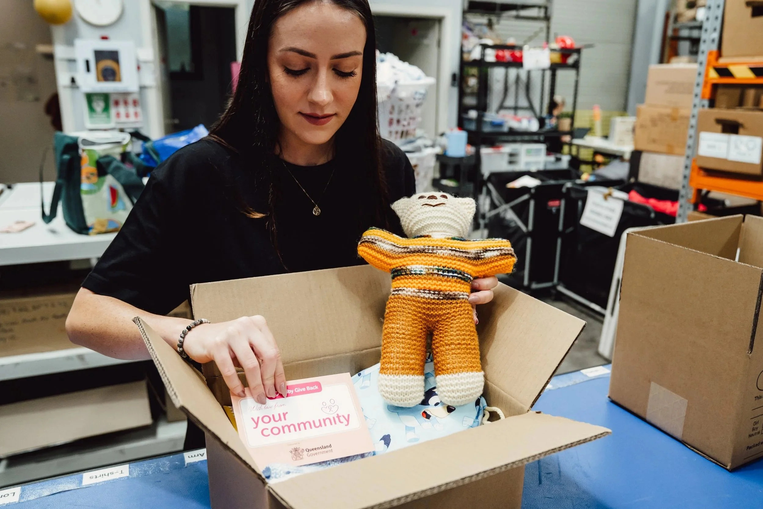 Volunteer carefully packing safe start box with community information and knitted toy