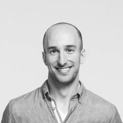 Black and white portrait of a smiling man in a button-up shirt.
