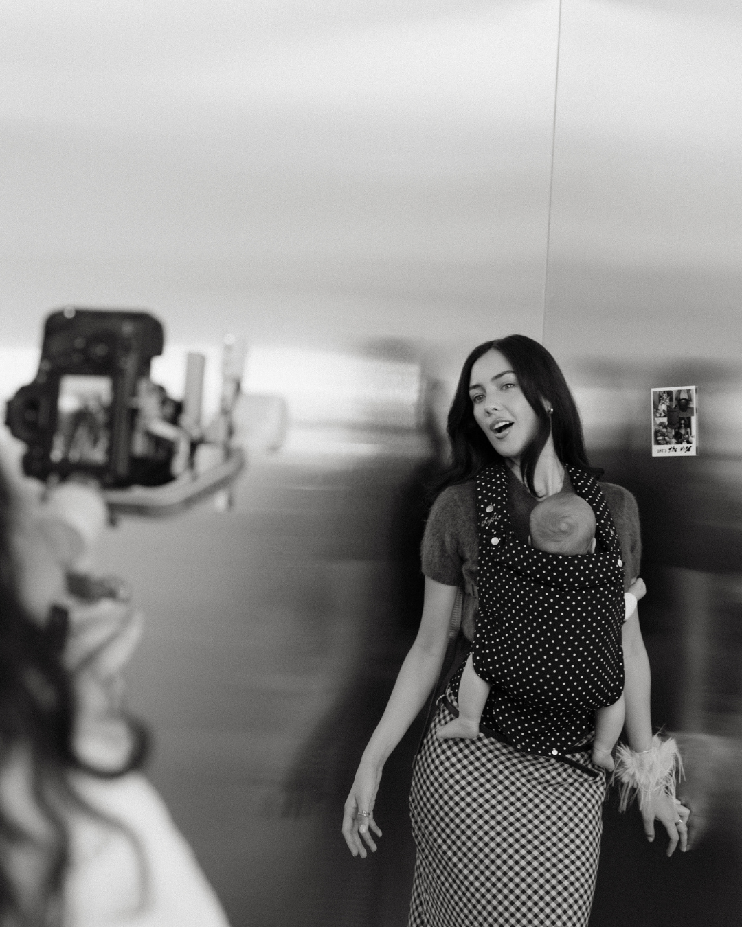 Natural light photo studio with stainless steel wall in the corner as a backdrop to a mother and baby being photographed 