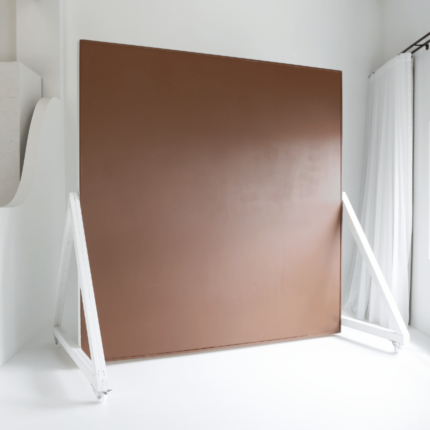 Extra large brown, double sided movable wall back drop on wheels. Posed on seamless white cyclorama wall.