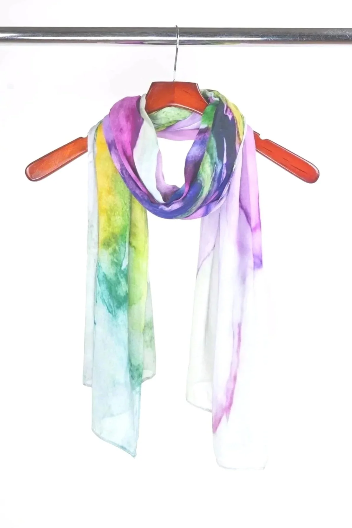 A colorful watercolor scarf draped over a wooden hanger on a metal rod, with a plain white background.