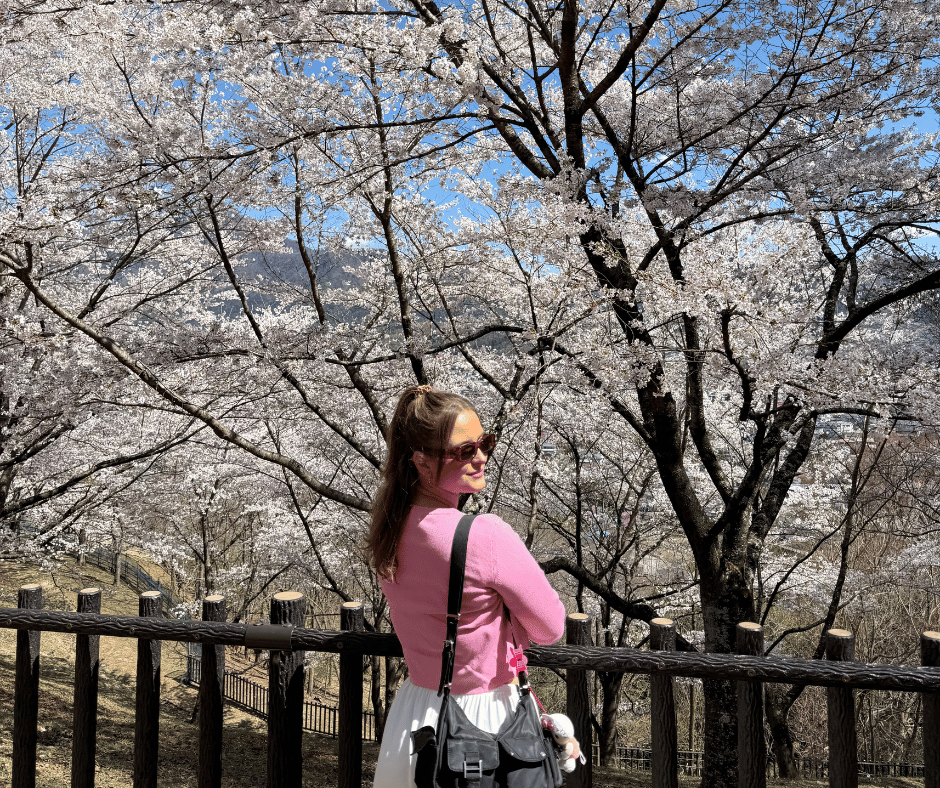 Gabi standing in front of a cherry blossom tree in Japan during sakura season, highlighting a safe and beautiful experience for solo female travellers.