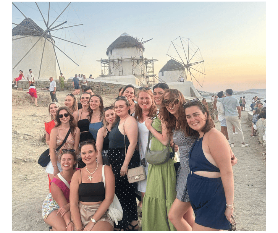 Group of solo female travellers at the Mykonos windmills at sunset, showcasing a fun, safe and social atmosphere for women exploring Greece.