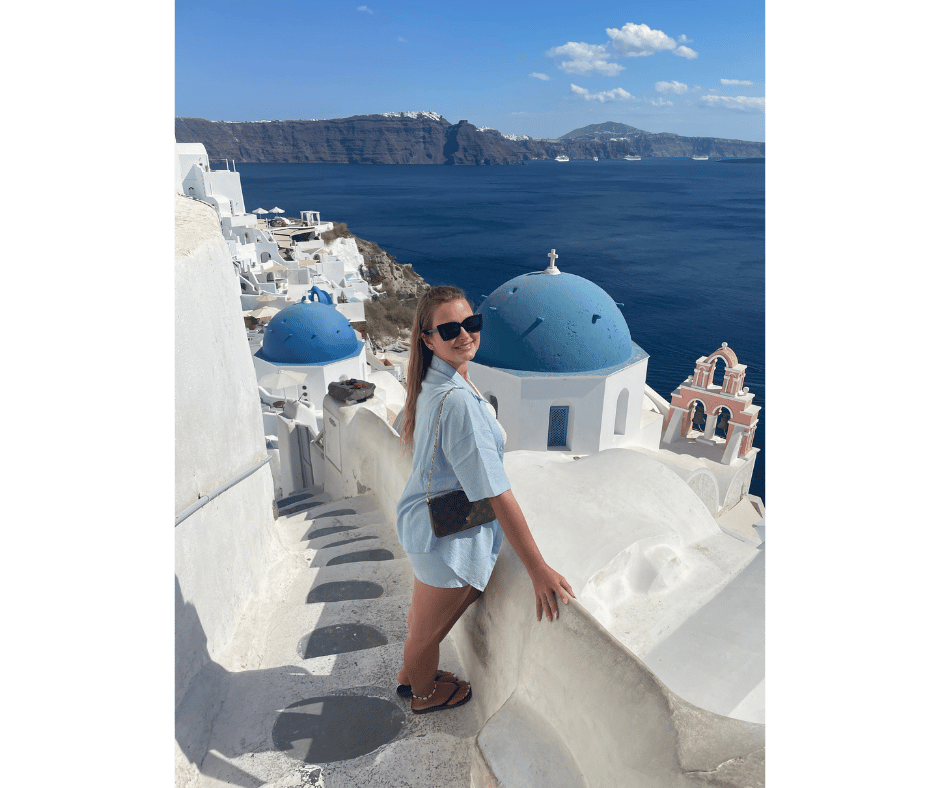 Solo female traveller overlooking the blue-domed churches in Oia, Santorini with caldera views, showcasing a safe and scenic Greek island for women travelling alone.