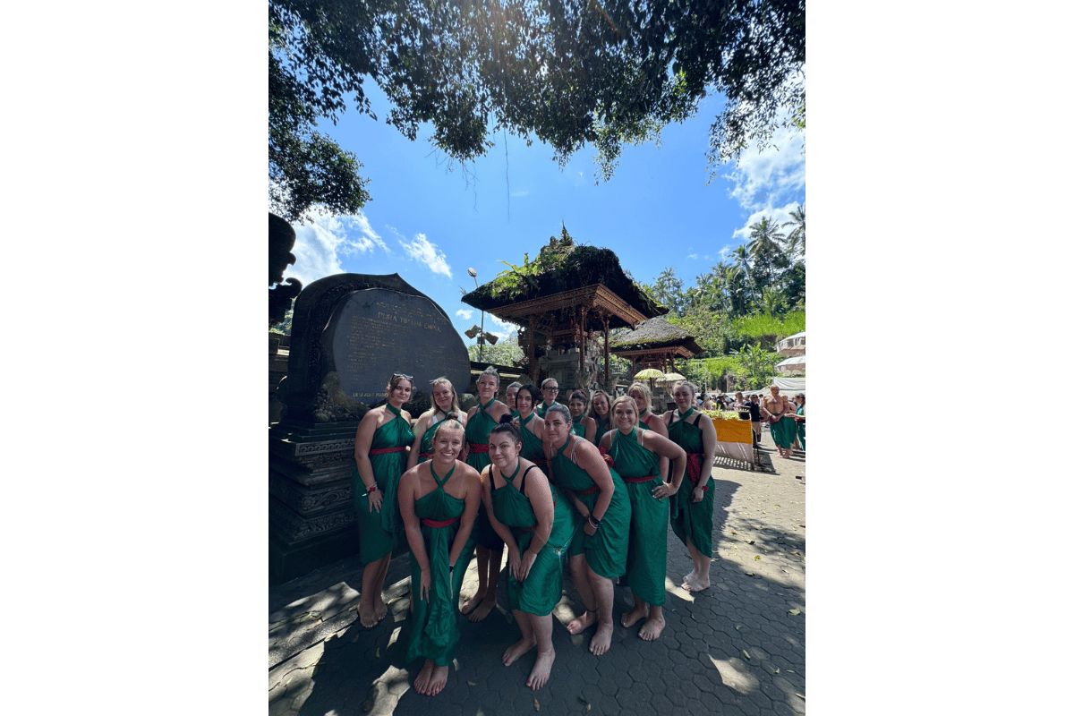 Group of female travellers visiting a Bali temple wearing modest outfits and sarongs, showing appropriate temple dress code for women.