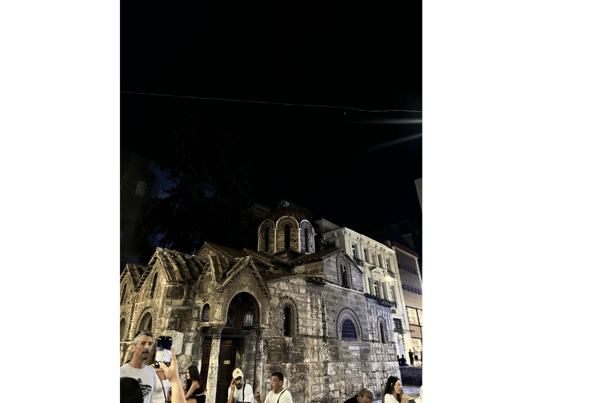 Female traveller visiting a church or monastery in Greece wearing modest clothing with shoulders and knees covered.