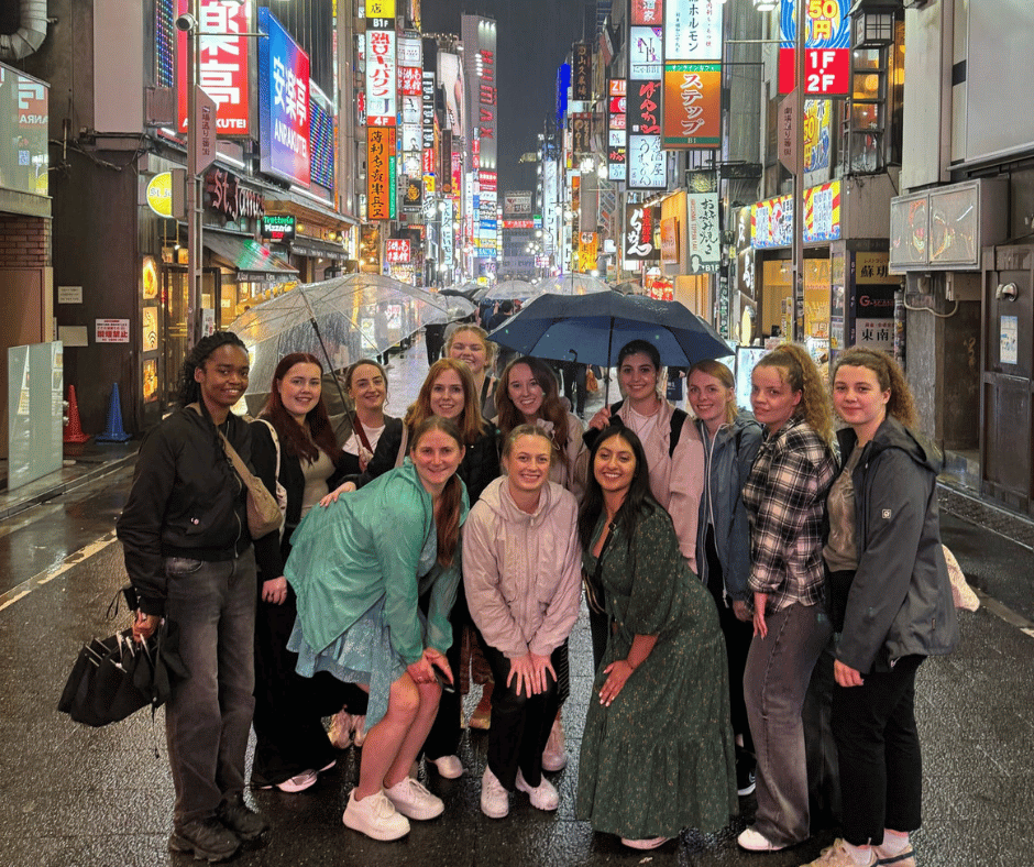 Group of solo female travellers exploring Shinjuku at night in Tokyo, showcasing the safe and vibrant atmosphere for women visiting Japan during cherry blossom season.