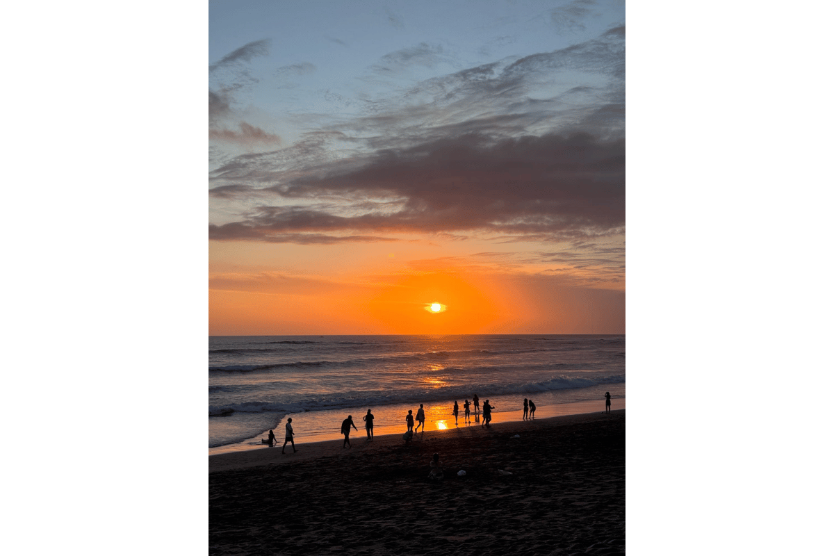 Sunset over a Bali beach with golden skies and calm waves, a peaceful moment during a solo female trip to Bali.