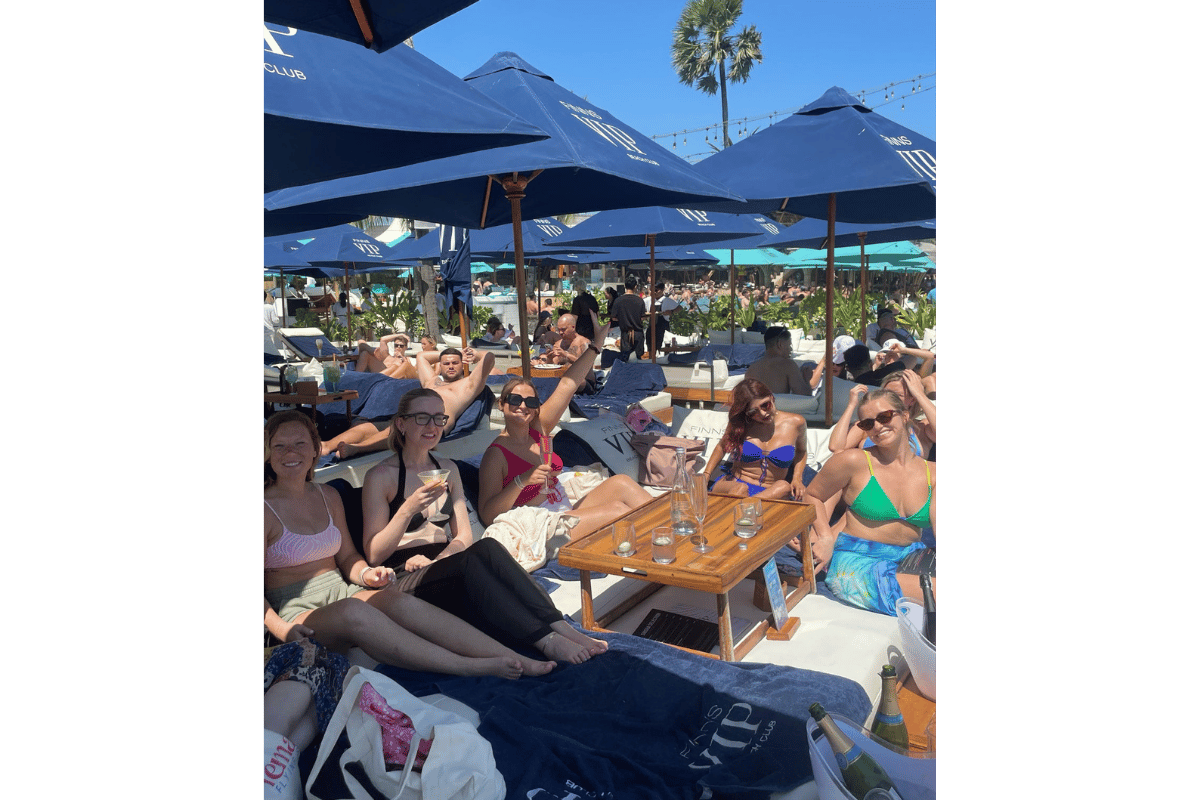 Group of female travellers enjoying a beach club in Bali, wearing swimwear and summer outfits during a solo female travel trip.