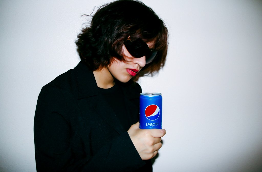 Editorial portrait of a person in a black jacket holding a blue Pepsi can—set against a soft, neutral background. The image merges fashion and branding, highlighting a pop culture icon through minimalist composition and confident styling.
If you'd li