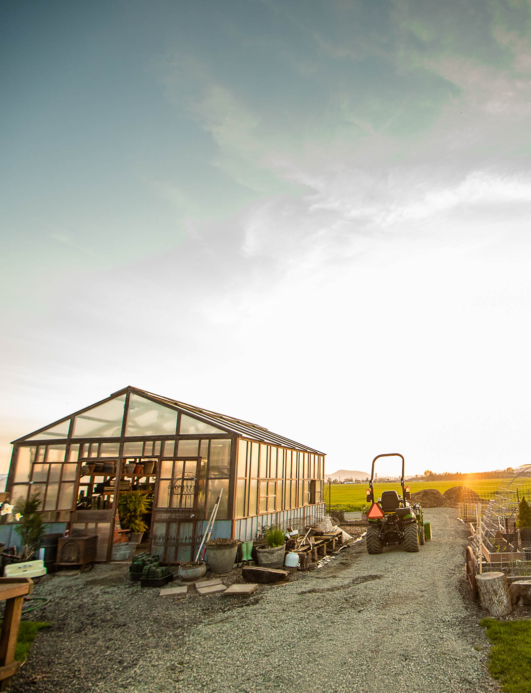 Invernadero en un campo con tractor y puesta de sol