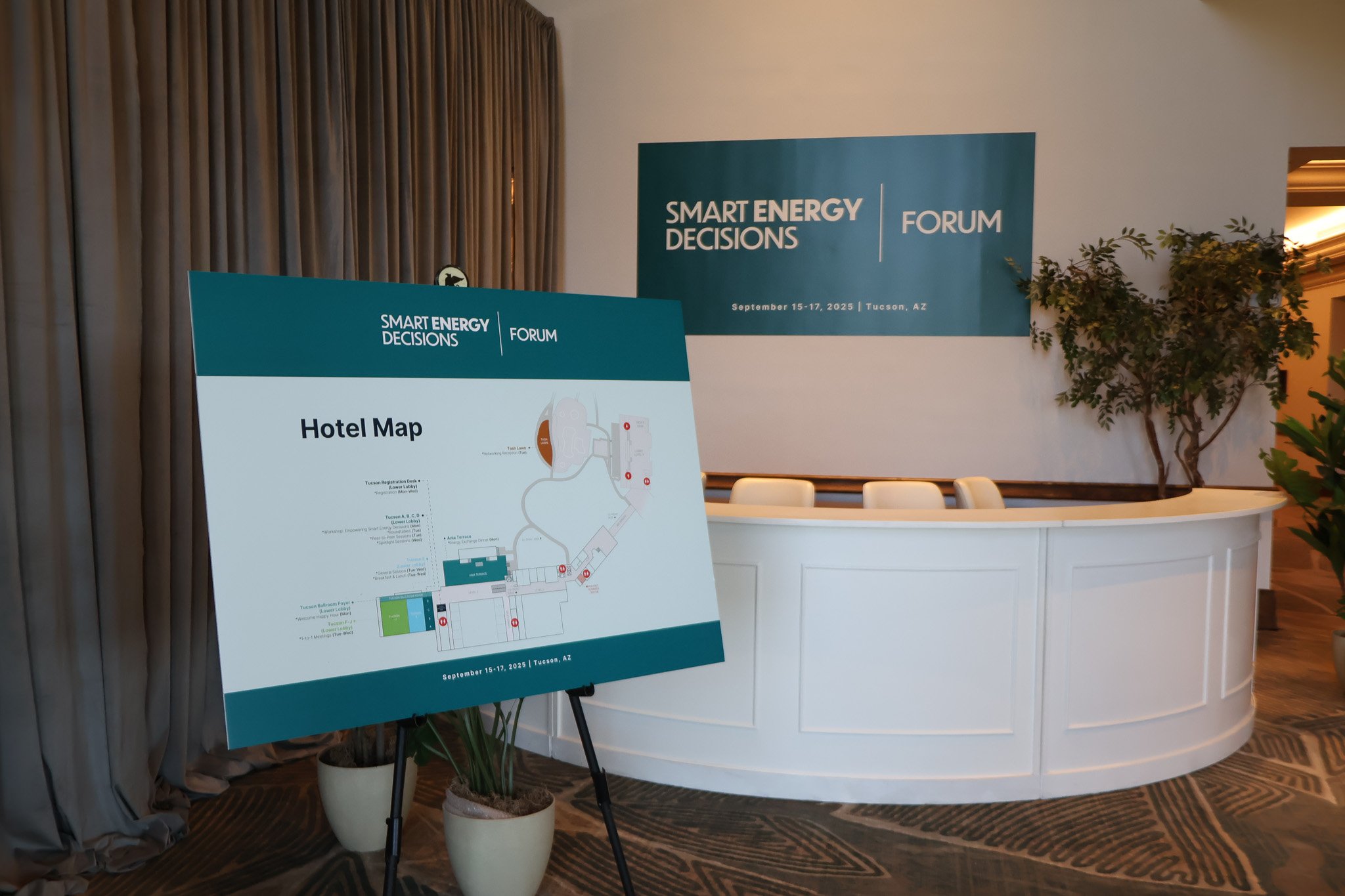 Hotel map at the Smart Energy Decisions forum held in Tucson, AZ from September 15-17, 2025, displayed on an easel near a white reception desk, with a blue banner in the background.