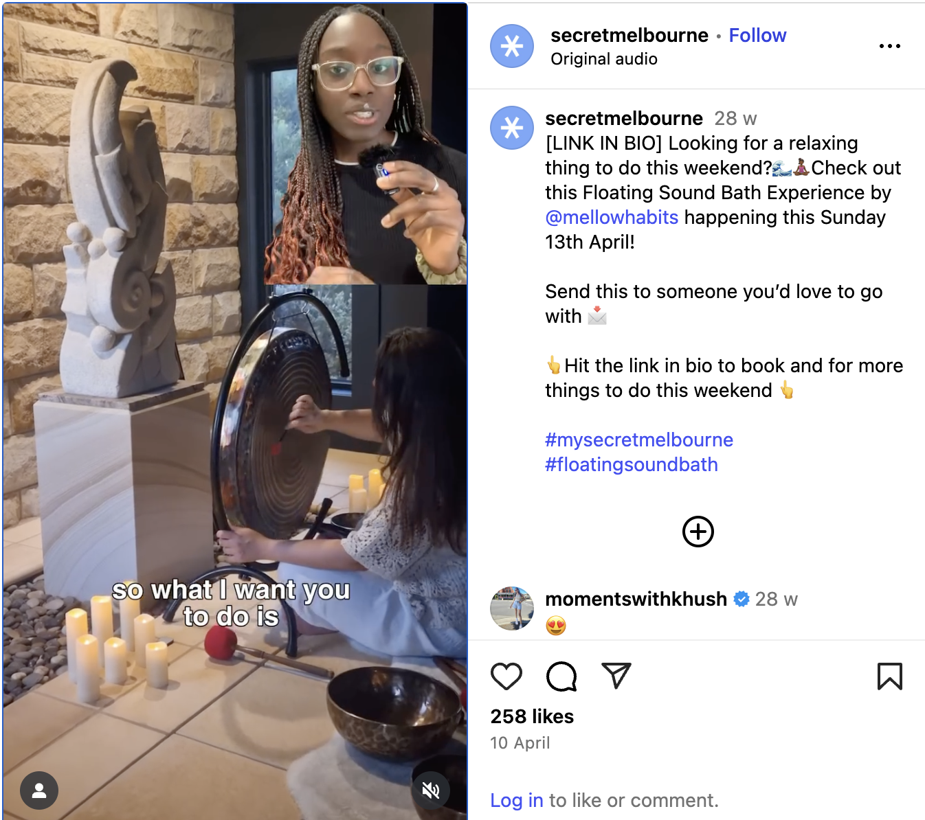 A woman with glasses and braided hair is speaking into a microphone, standing next to a stone wall, with a window in the background.