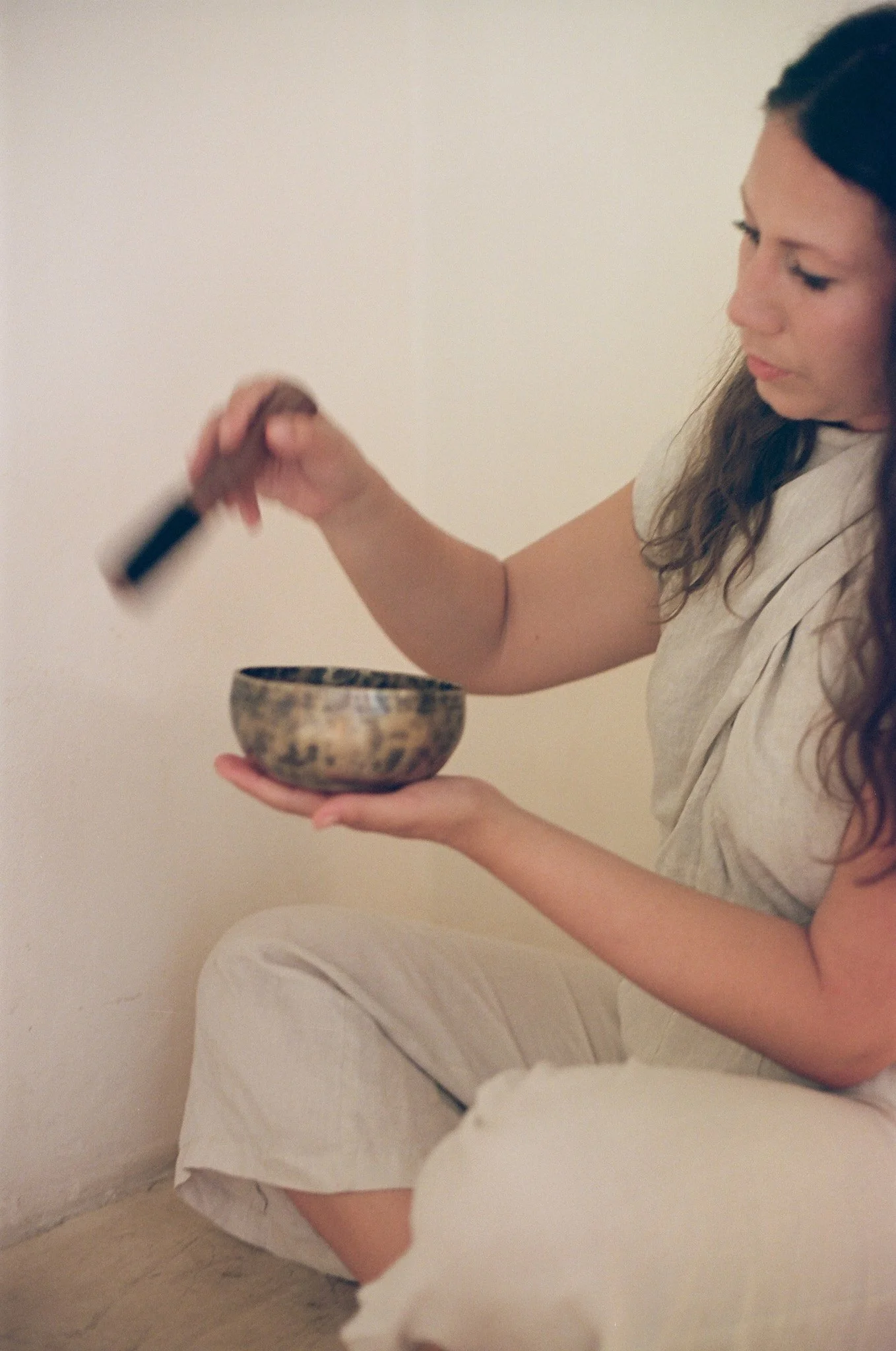 A woman sitting on the floor with a Tibetan sining bowl hosting a sound meditation in Australia.