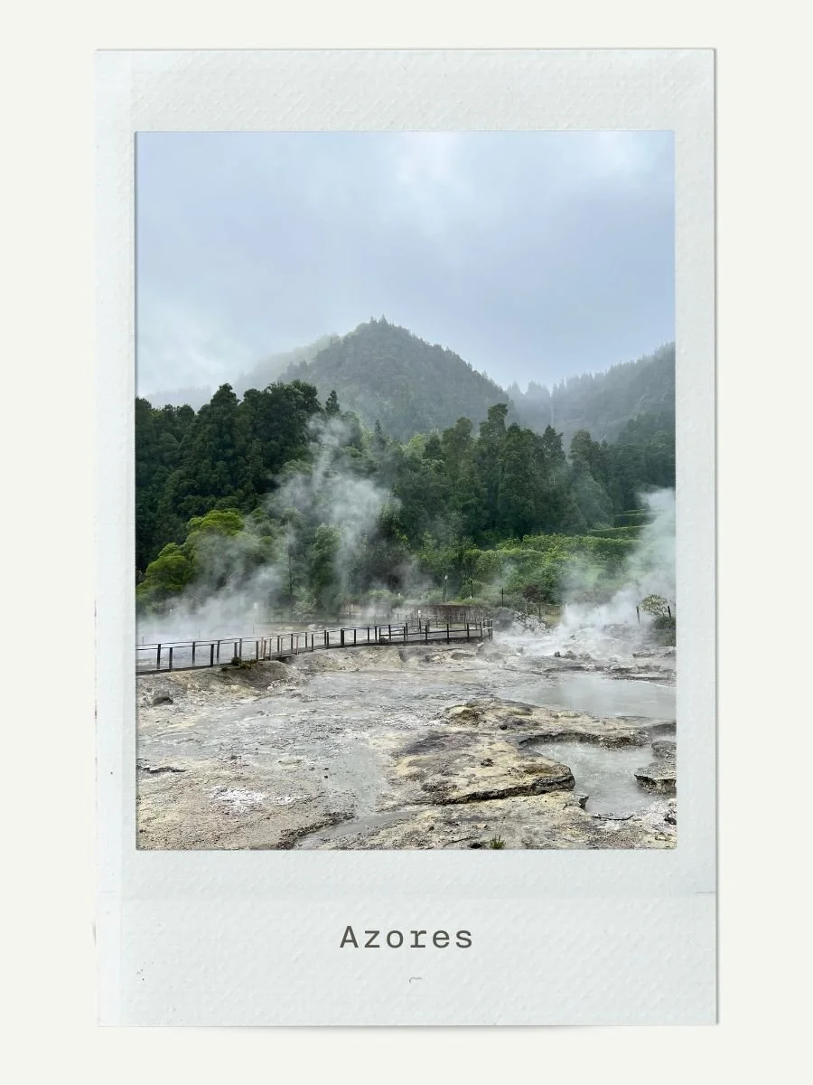 Hot springs with steam rising, surrounded by lush green mountains in the Azores.