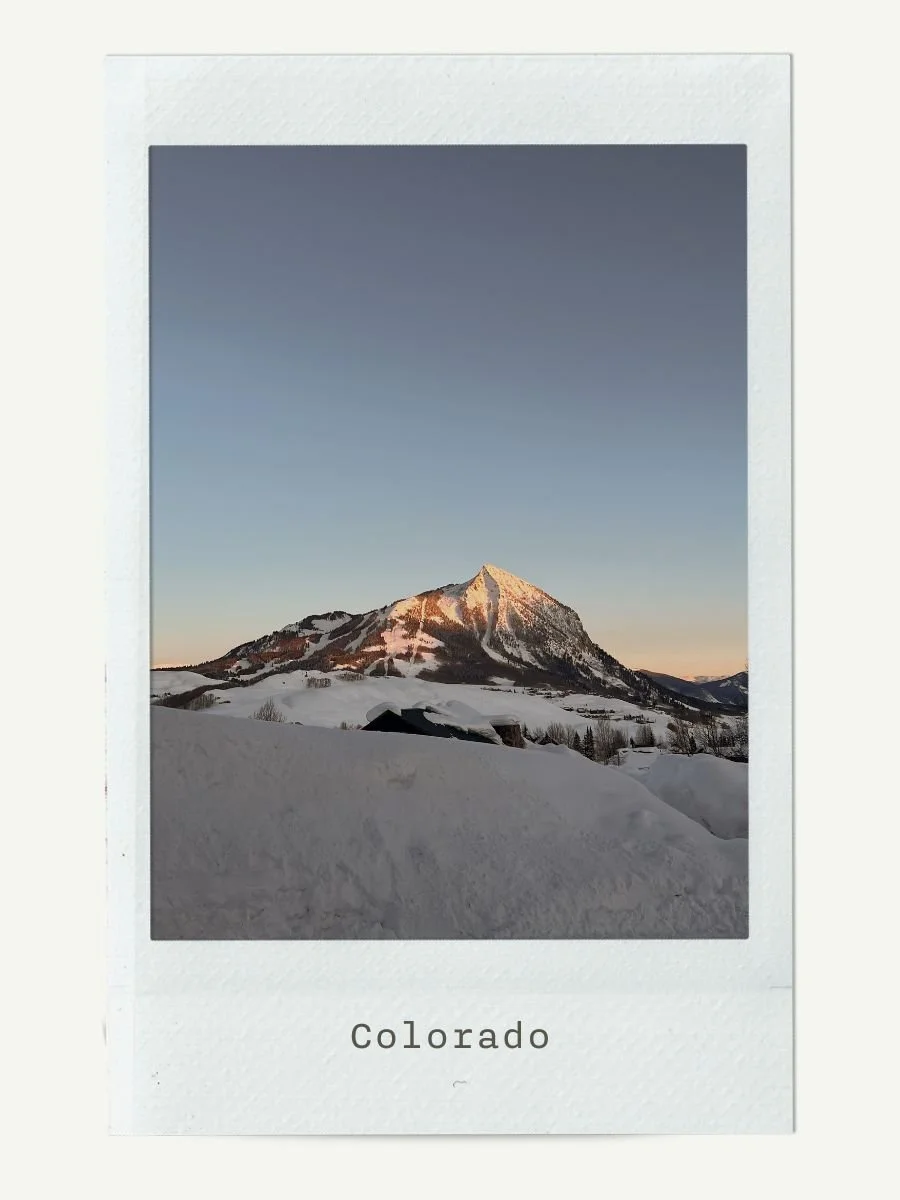 Snow-covered mountain in Colorado during sunset or sunrise with clear sky above.