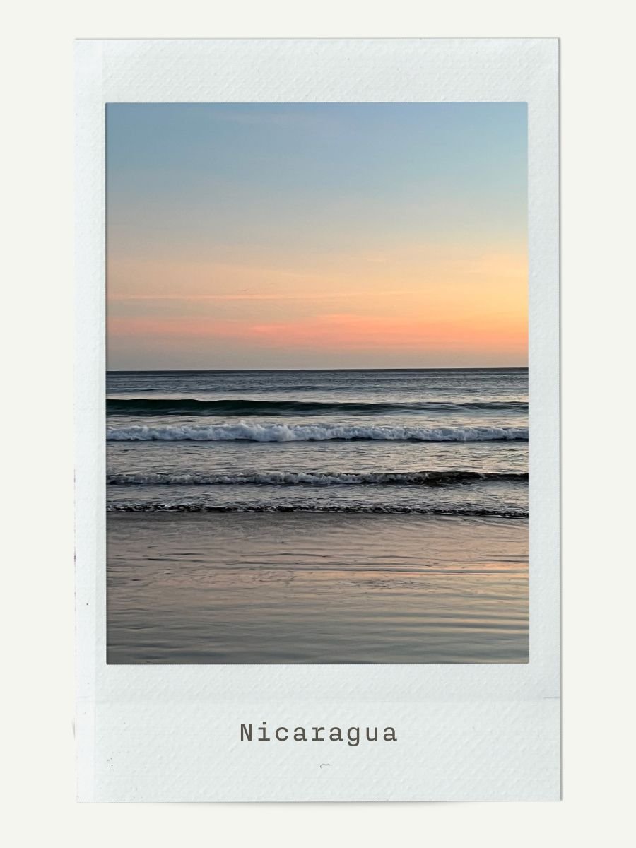 Sunset over the ocean in Nicaragua with gentle waves and colorful sky.