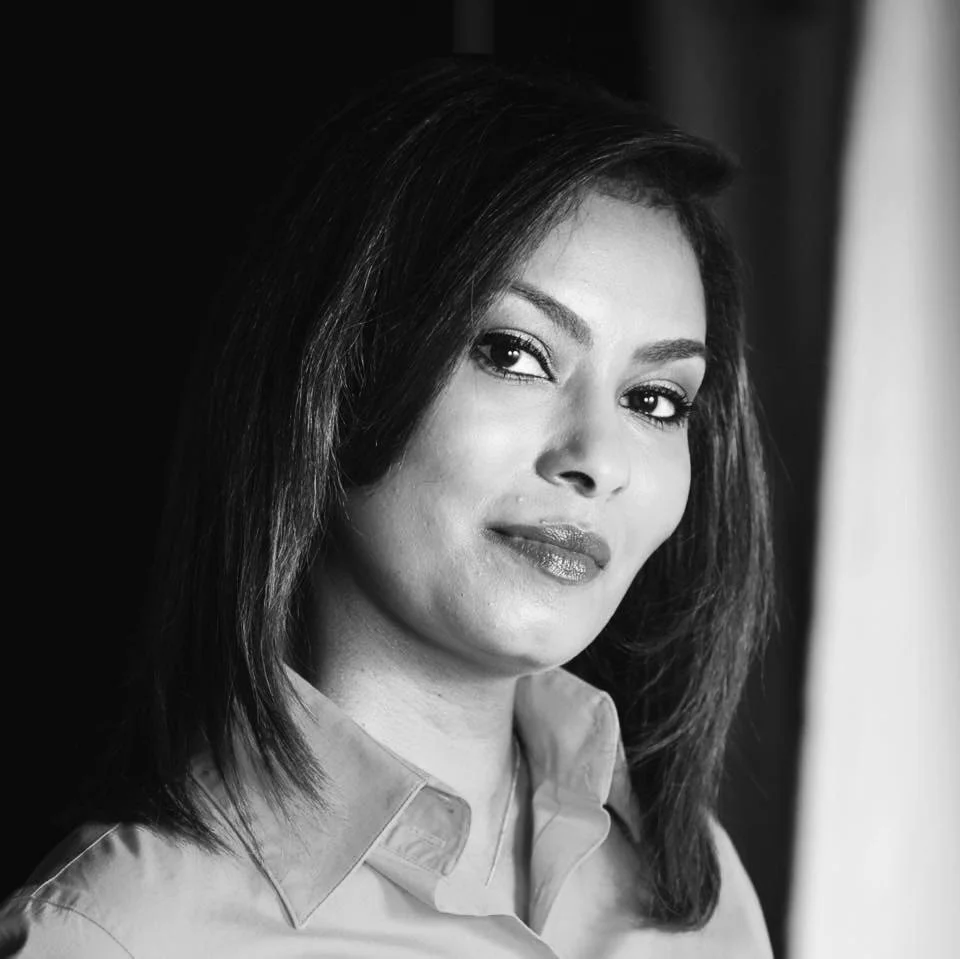 Black and white portrait of a woman with shoulder-length hair, wearing a collared shirt, looking at the camera with a slight smile.