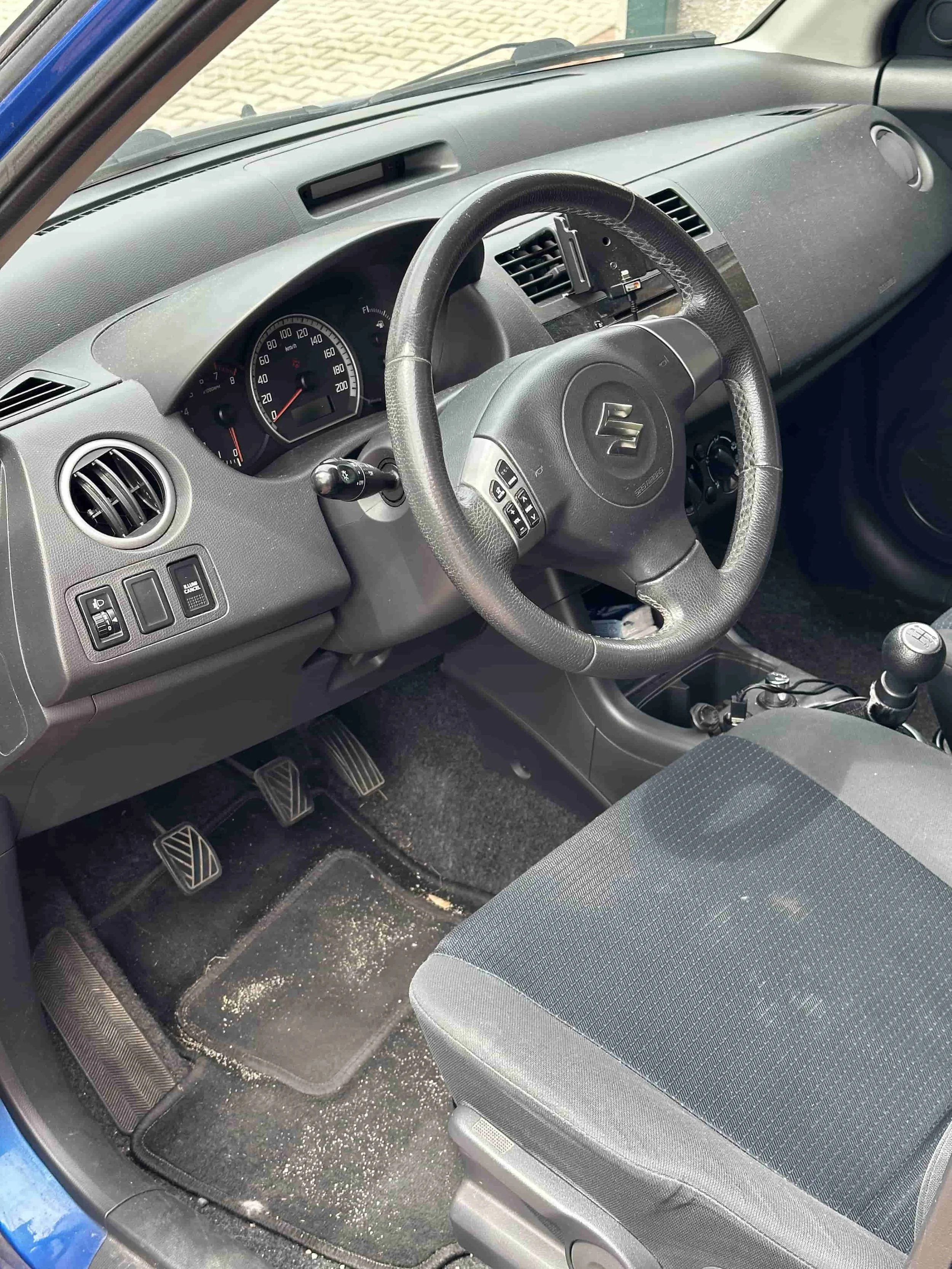 Interiér Suzuki před čištěním – běžné znečištění a prach v interiéru.