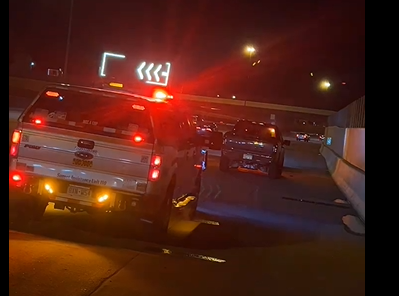Flat tire on a silver car with visible wheel rim, parked on rough pavement.