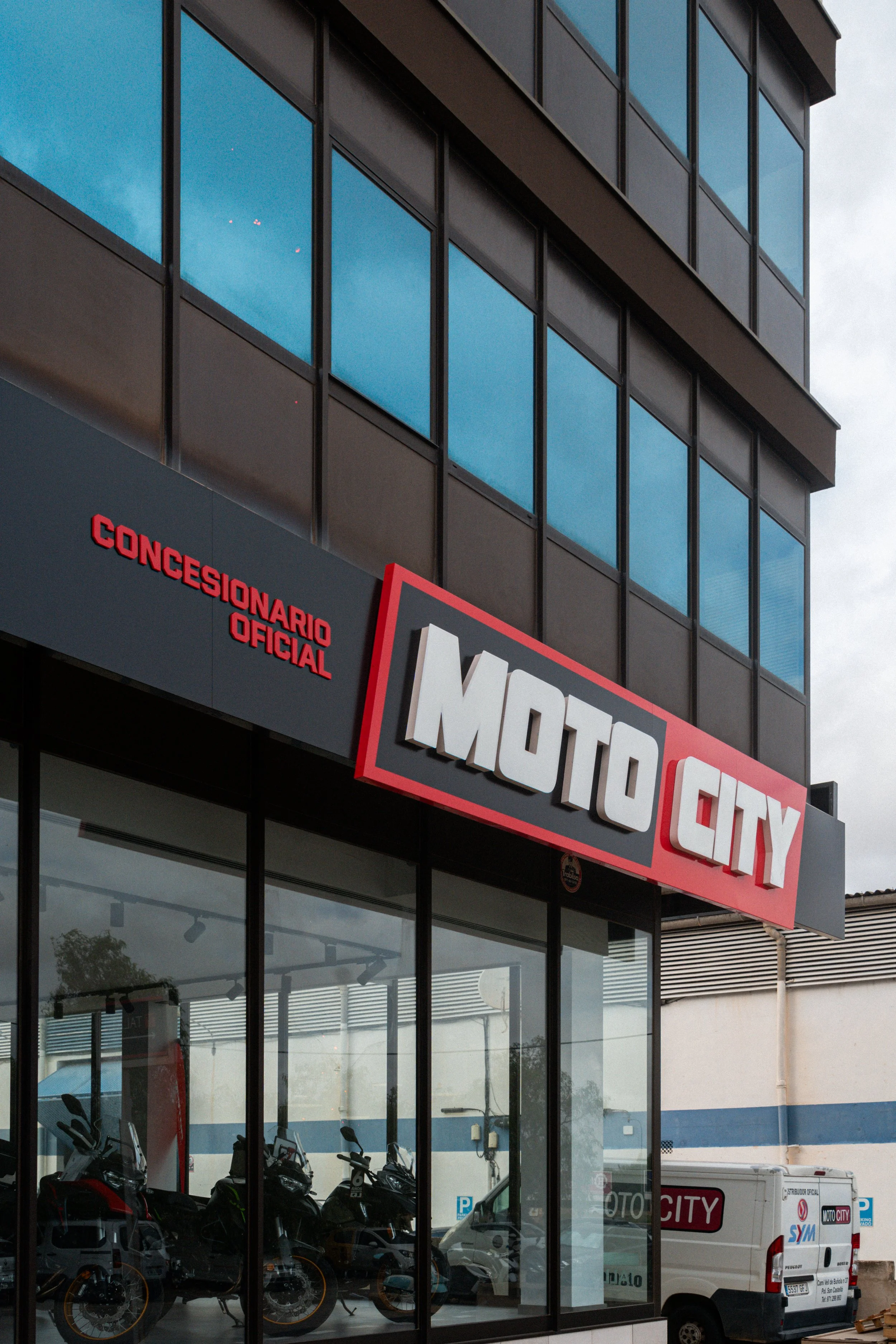 fachada de una tienda de motos llamada Moto City en un edificio con ventanas de vidrio